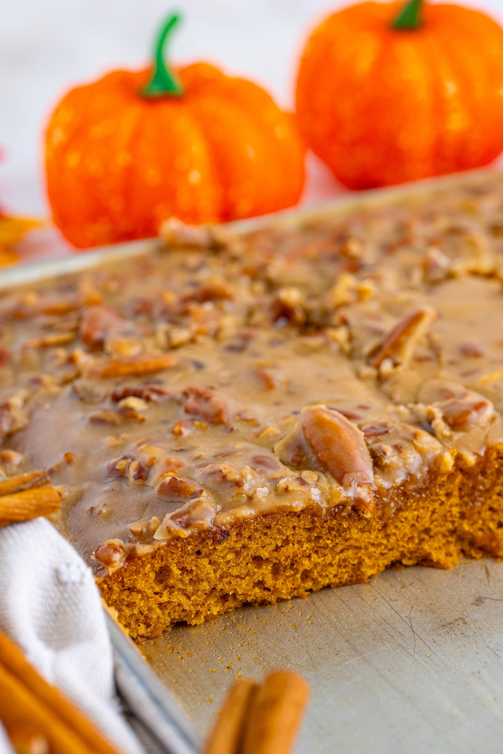 Pumpkin Snack Cake with Praline Icing in a sheet pan with a few slices of the cake removed from the pan