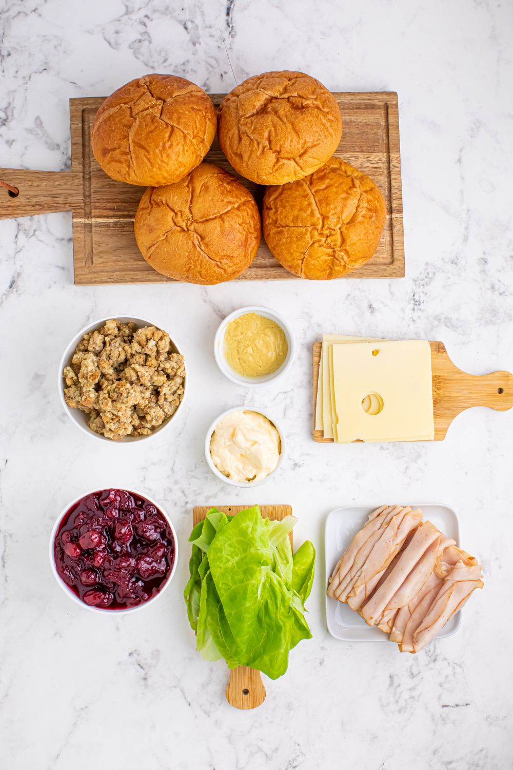 ingredients for leftover Turkey Sandwiches on table. Cranberry, stuffing, turkey, cheese, lettuce, rolls, condiments 