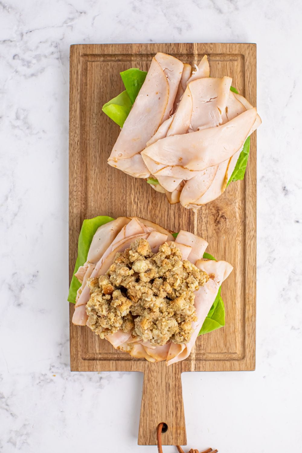 Leftover Turkey Sandwiches being assembled with meat and stuffing on the sliced roll 