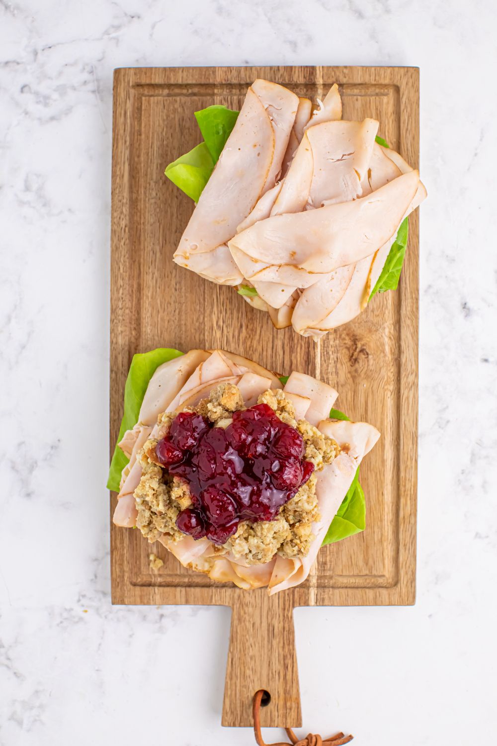 turkey sandwich being assembled with cranberry sauce on top 