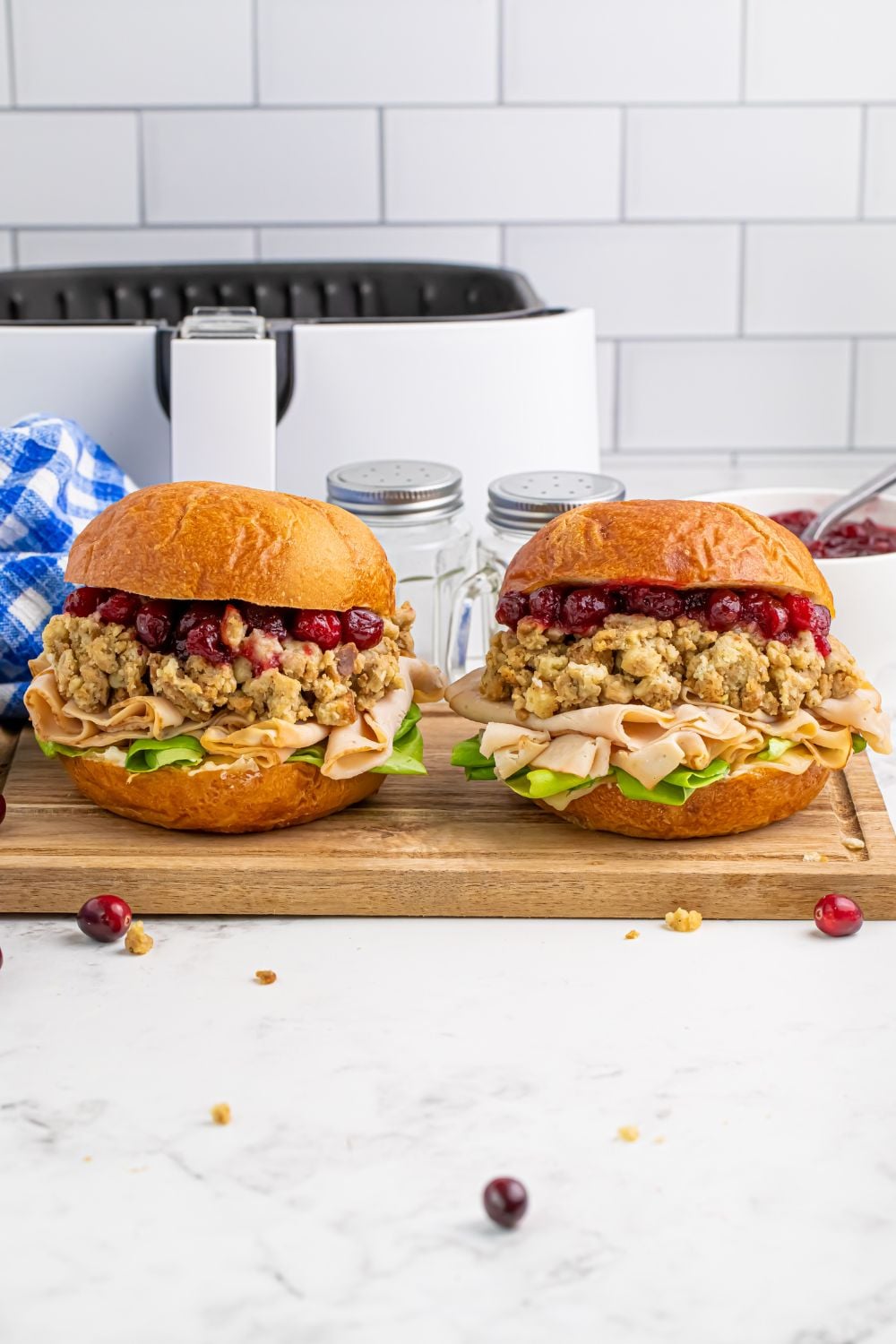 Leftover Turkey Sandwiches sitting on a cutting board on the table with some cranberries on table 