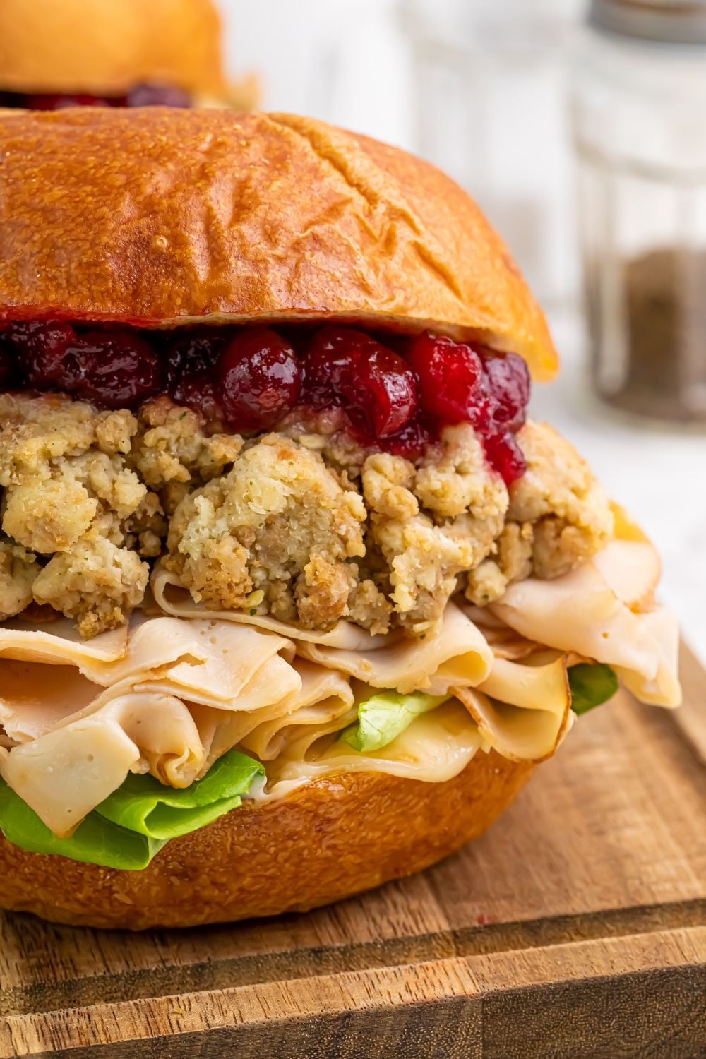 side view of Leftover Turkey Sandwich sitting on a wooden cutting board on table 