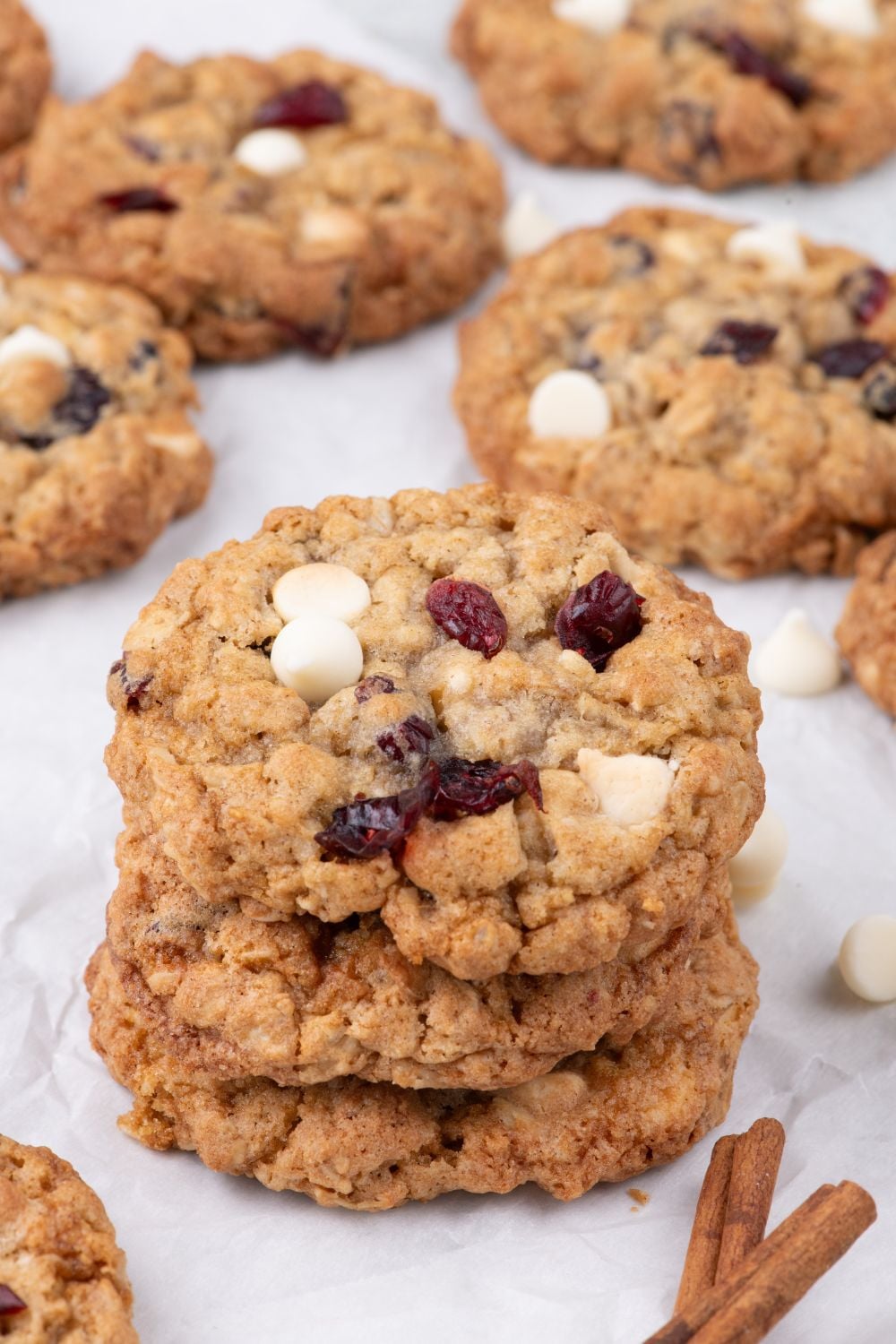 White Chocolate Cranberry Oatmeal Cookies stacked on table with some cookies spread out on counter around the stack