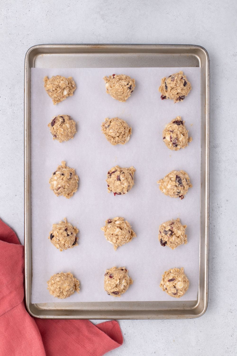 raw White Chocolate Cranberry Oatmeal Cookie dough in balls on a cookie tray on table