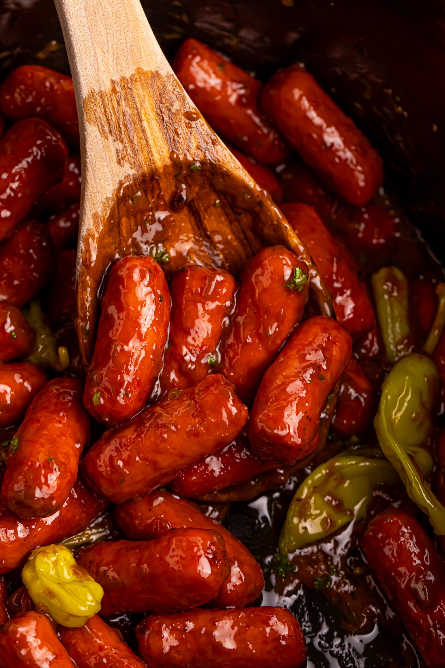Mississippi Lil Smokies in a slow cooker with a wooden spoon lifting up some 
