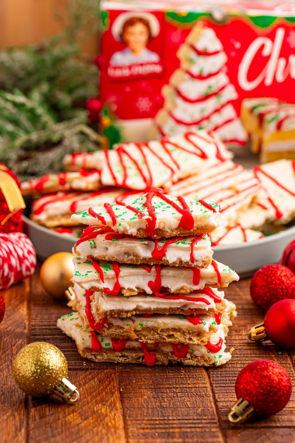 Christmas Tree Crack stacked in front with a bowl of more crack behind it and holiday decorations around the plate 