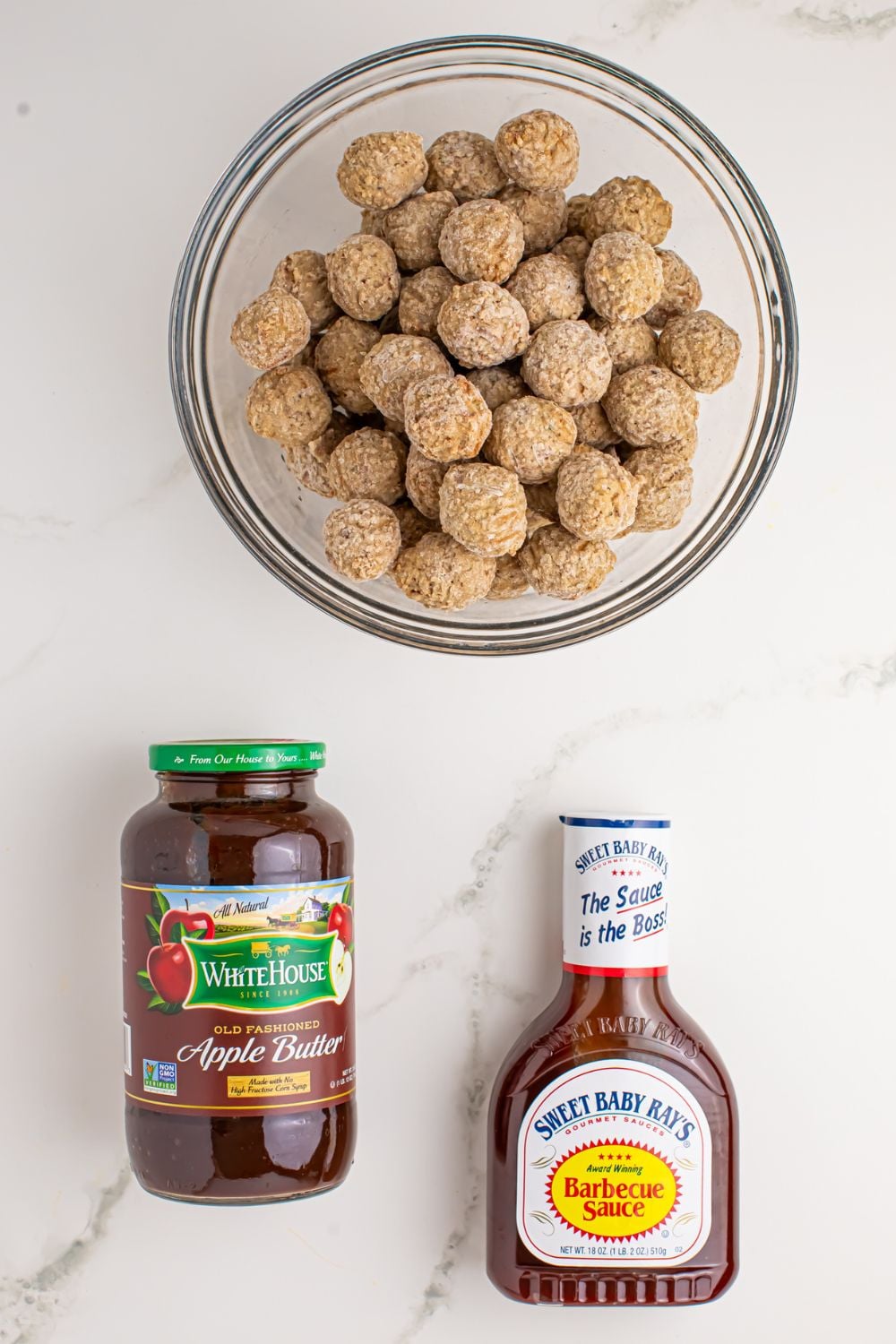 frozen meatballs in a bowl, apple butter and bbq sauce in jars under the meatballs