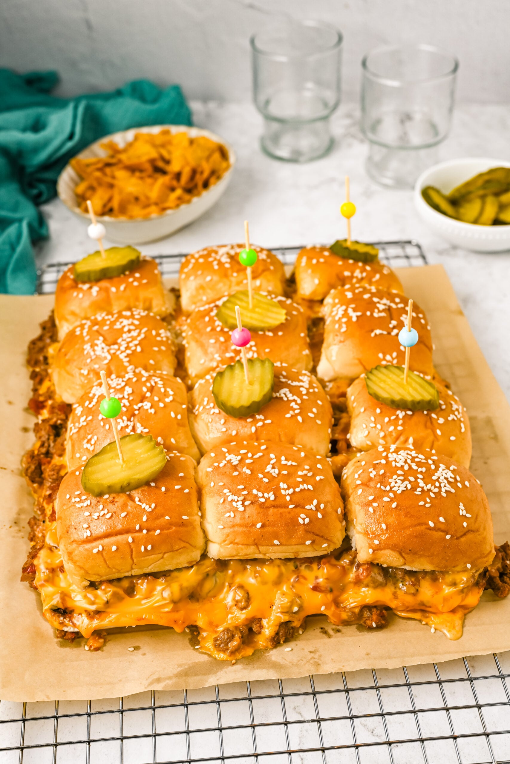 bacon cheeseburger sliders on a cookie sheet topped with pickles