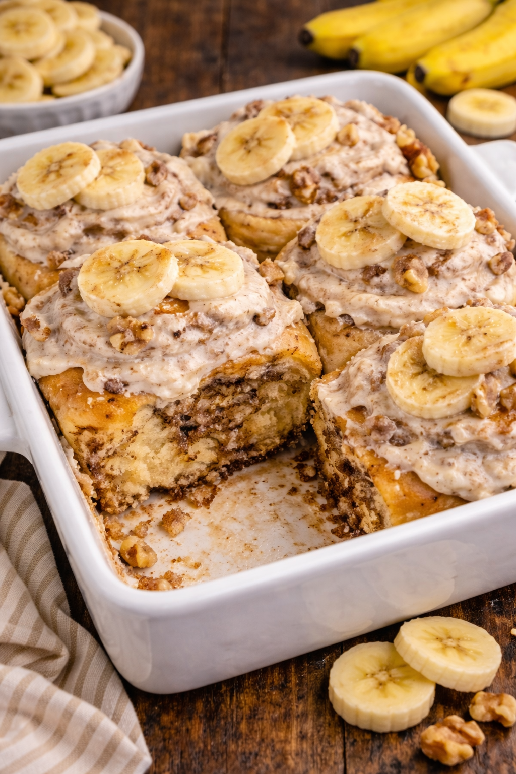 white baking dish full of Banana nut cinnamon rolls with one missing