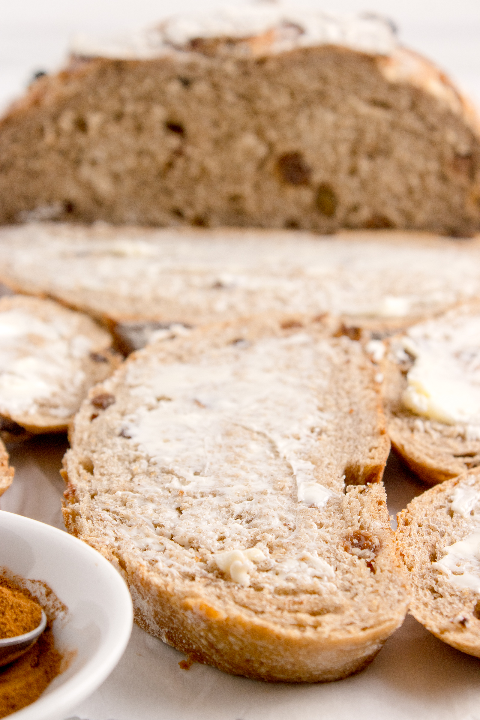 Cinnamon raisin bread on table with a piece covered in butter