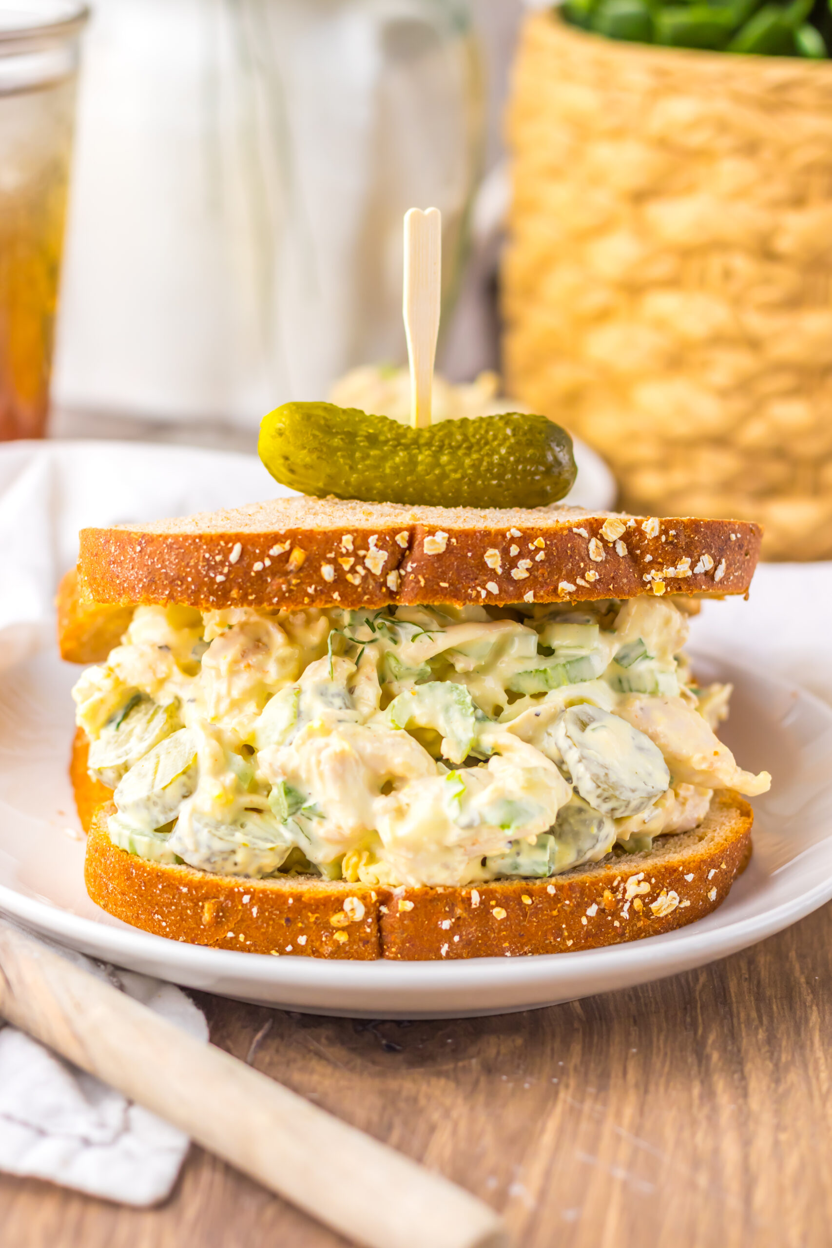 up close shot of the Pickle Chicken Salad sandwich on a white plate topped with a tiny pickle