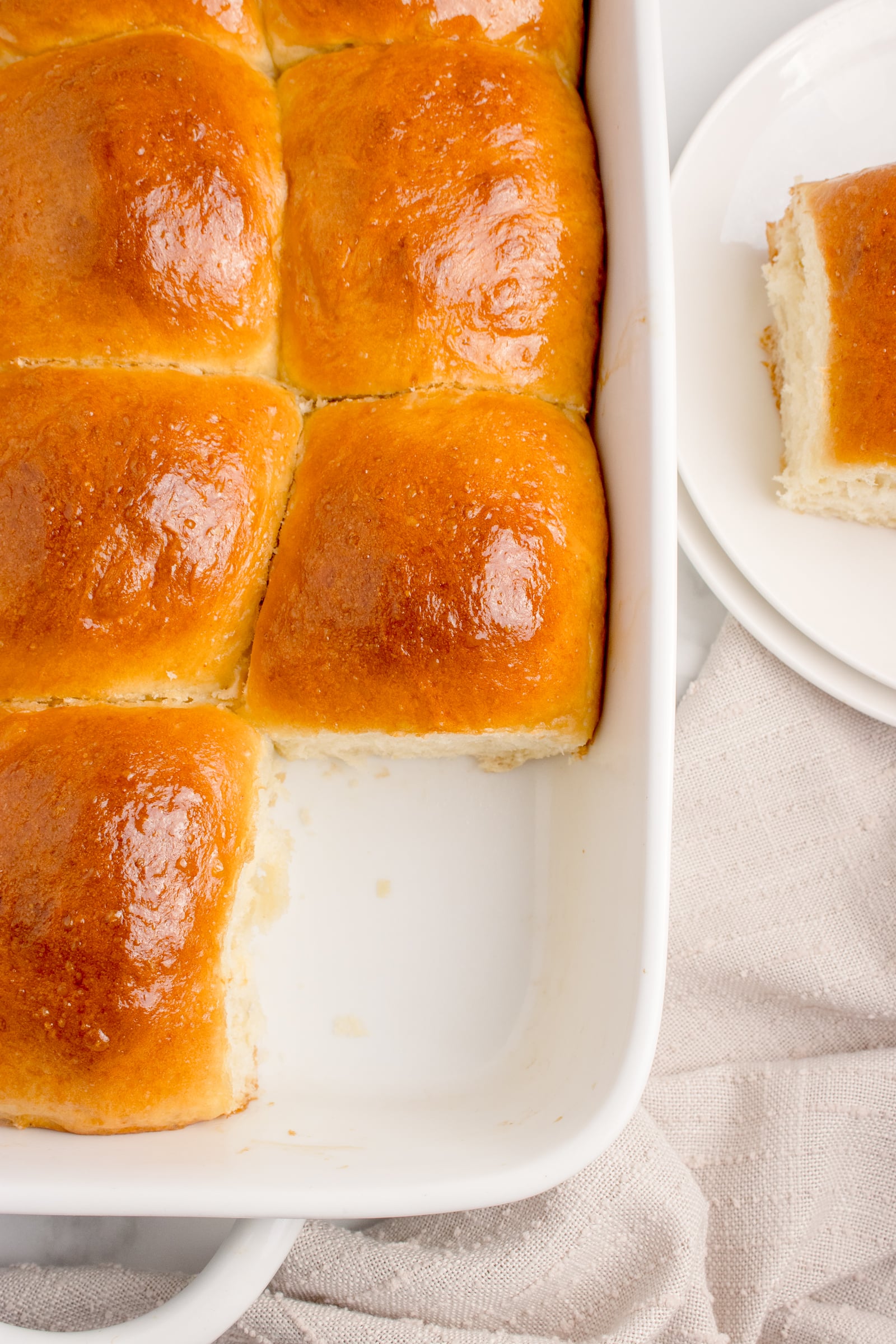 Pull Apart Dinner Rolls in a white baking dish with one removed