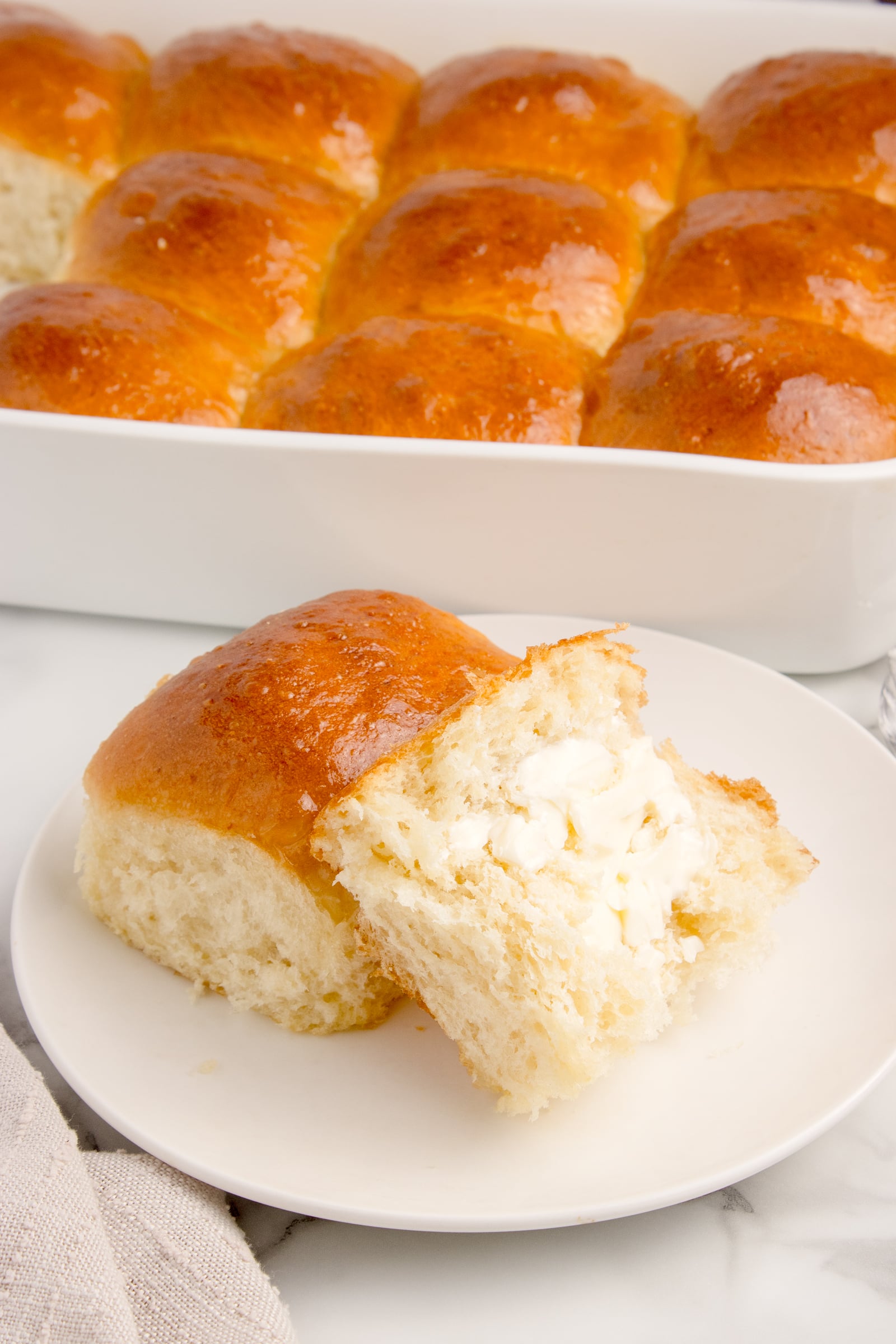 Pull Apart Dinner Rolls on a white plate with one cut in half and buttered