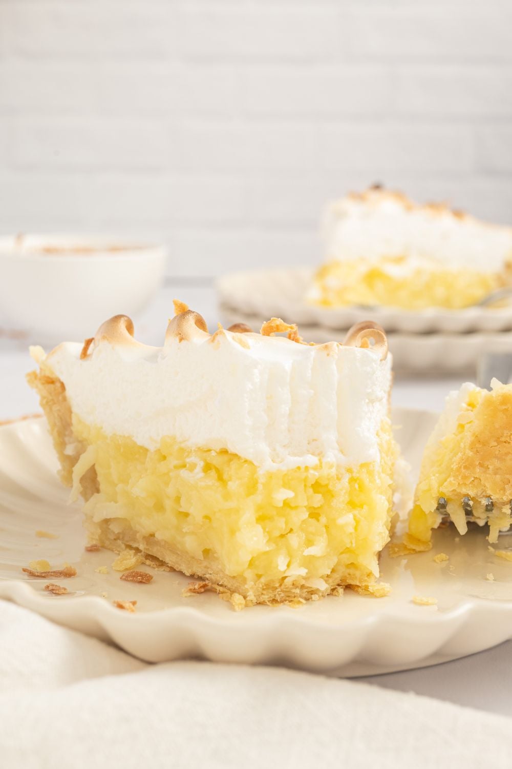 slice of Coconut Meringue Pie on plate with a fork with a bite full on it 