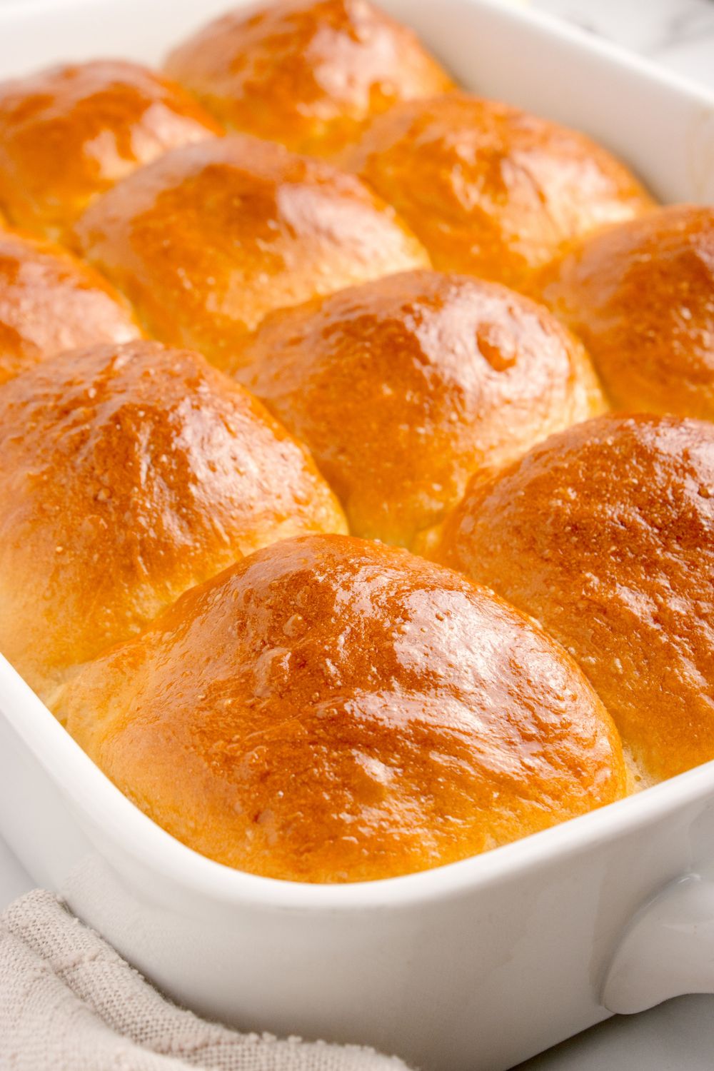 Pull Apart Dinner Rolls in a white casserole pan sitting on table showcasing the golden brown tops of the rolls