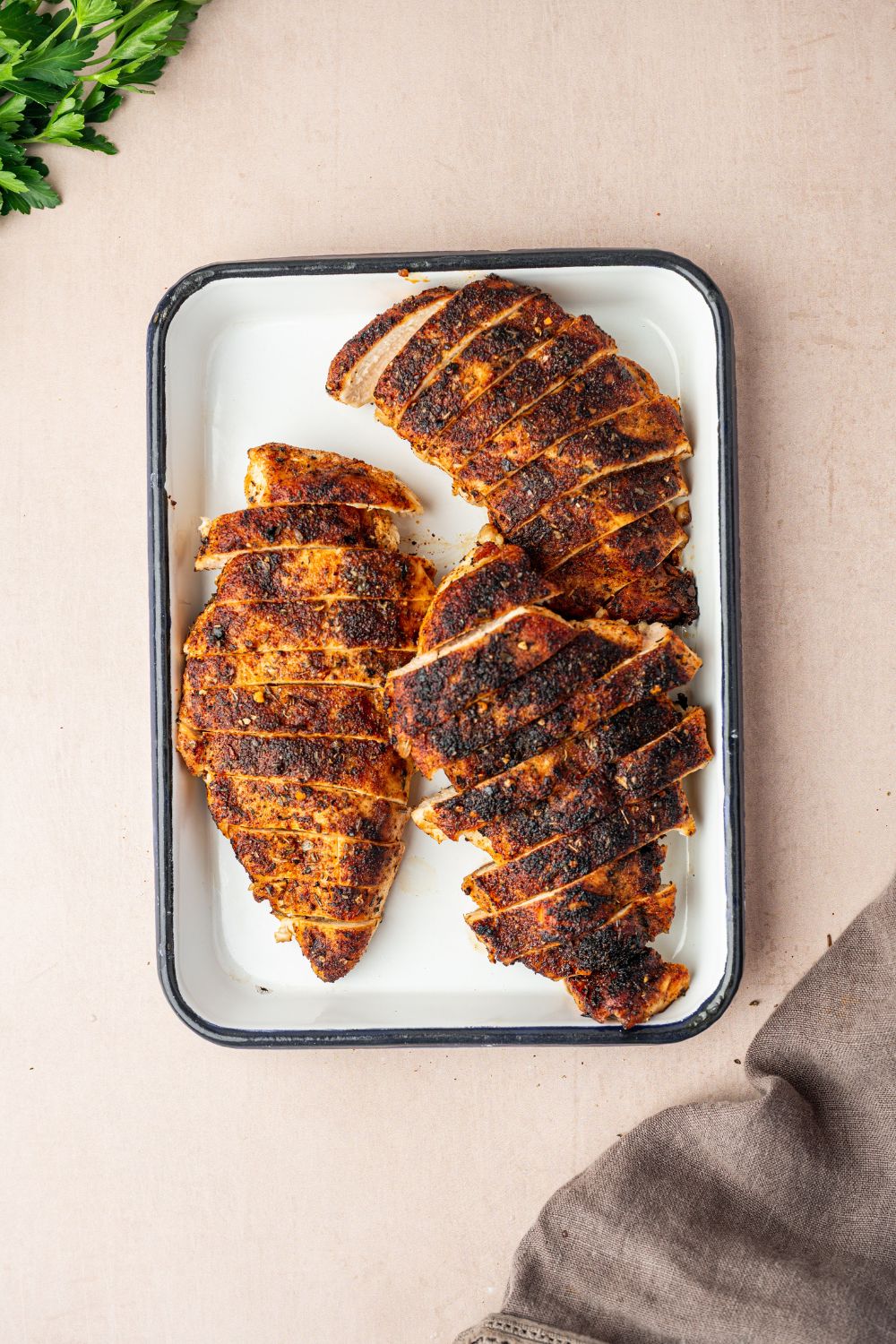 blackened chicken on a platter that is sliced into strips sitting on table 