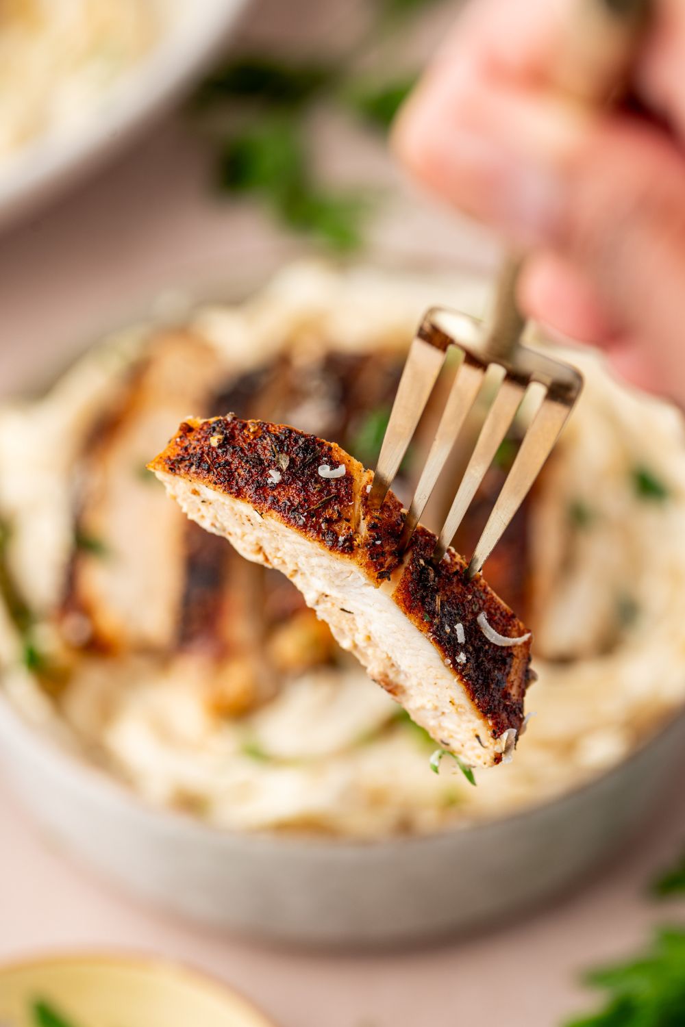 cajun chicken alfredo in a bowl with a fork with a piece of blackened chicken on it