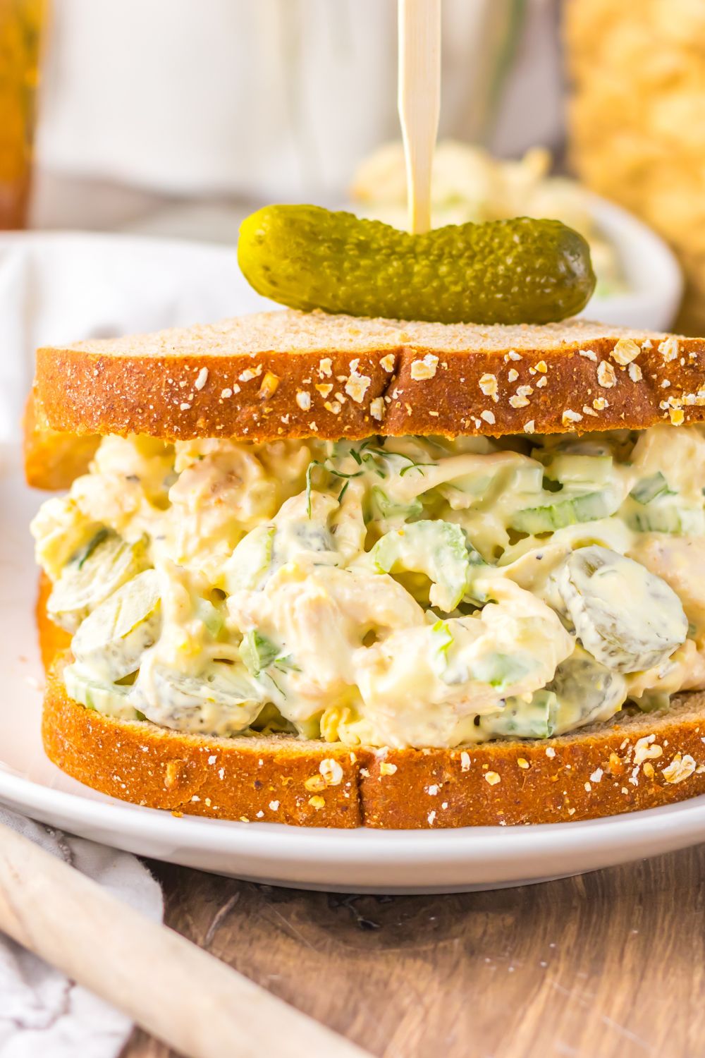 Pickle Chicken Salad on plate on bread with a pickle and toothpick in top 