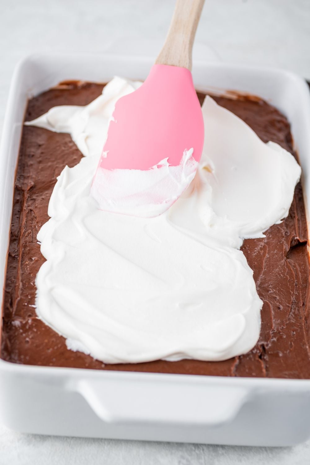 whipped cream being spread on top of pudding layer for the Chocolate Oreo Lush