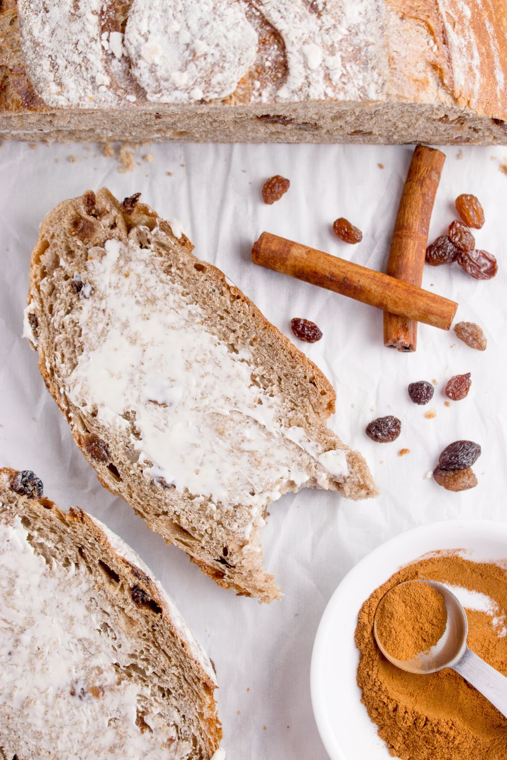 cinnamon raisin bread on table with butter spread on top and ingredients around it on table
