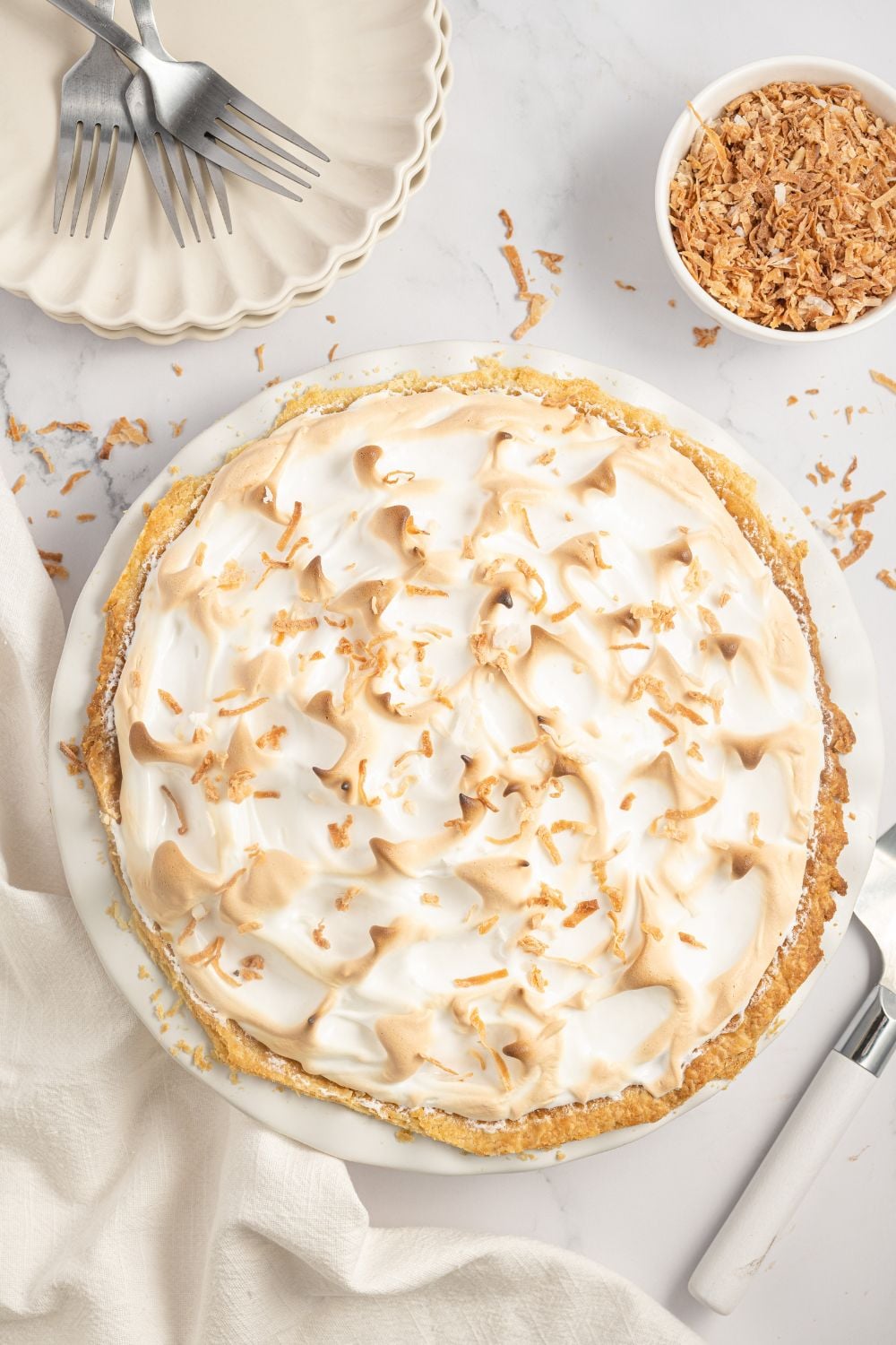 overhead Coconut Meringue Pie on table with toasted coconut around it on table 