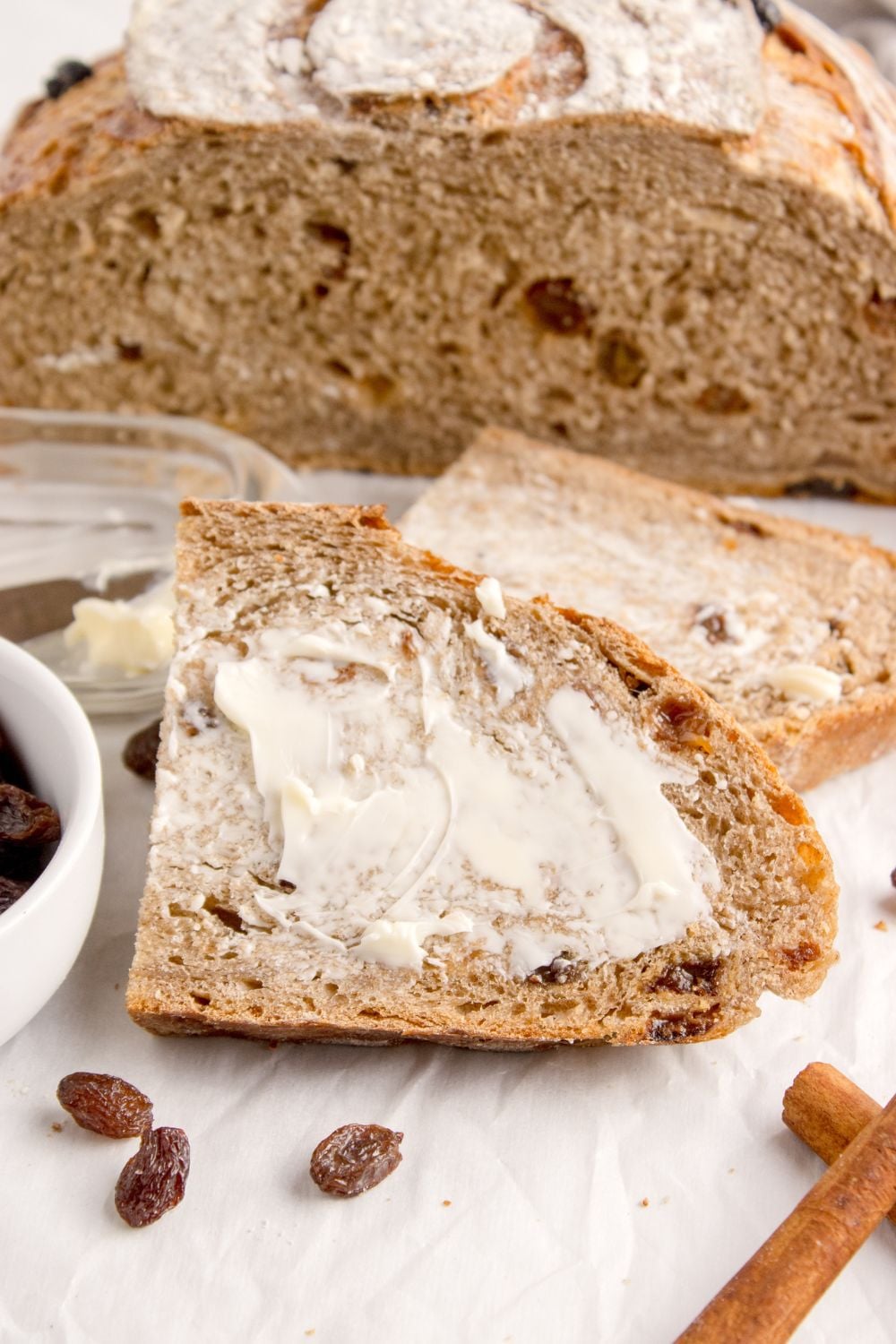 slice of cinnamon raisin bread with butter slathered on top of it