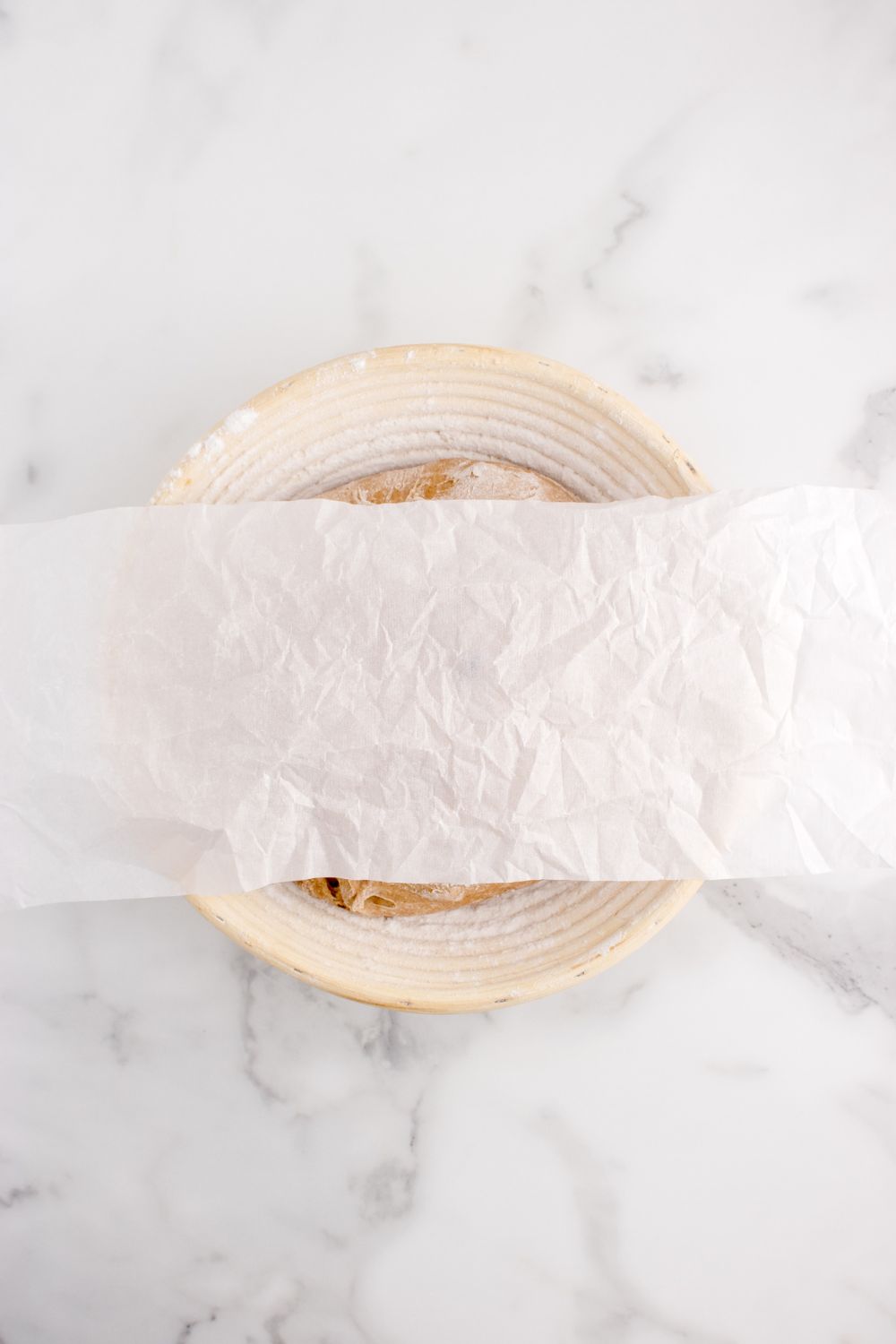 cinnamon raisin bread dough in a bowl covered with wax paper