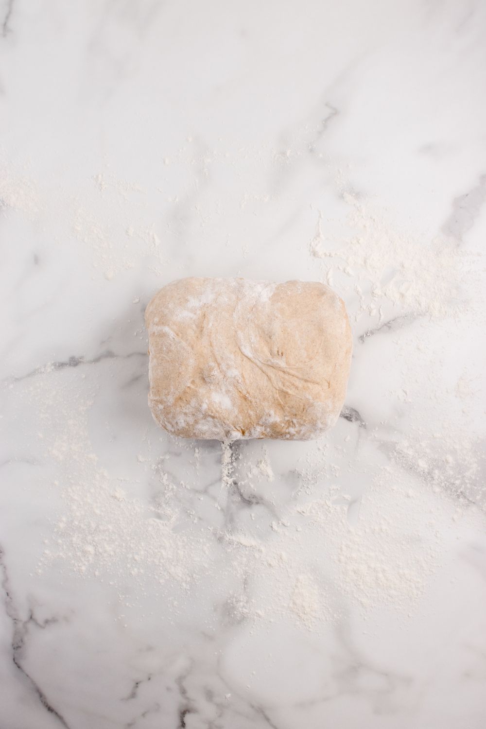 rolled bread dough on a marble countertop