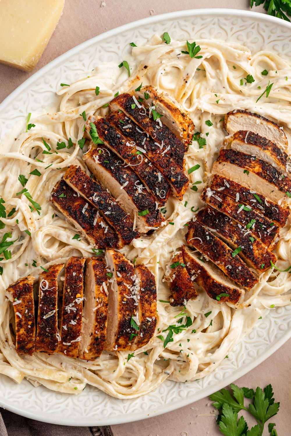 Blackened Chicken Alfredo in a large casserole dish with garnish on top of it 