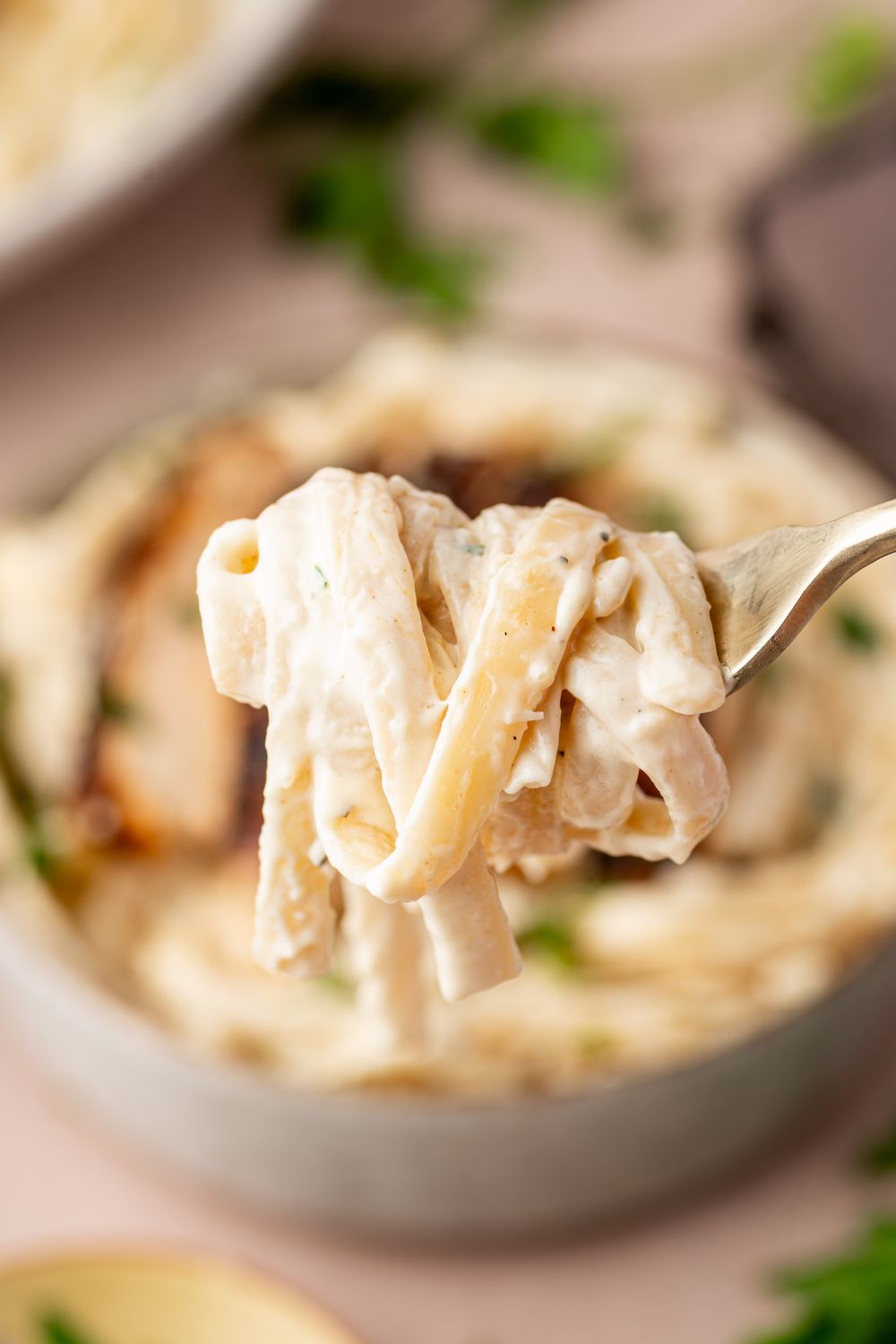 fettuccine noodles swirled on a fork above a bowl of pasta 