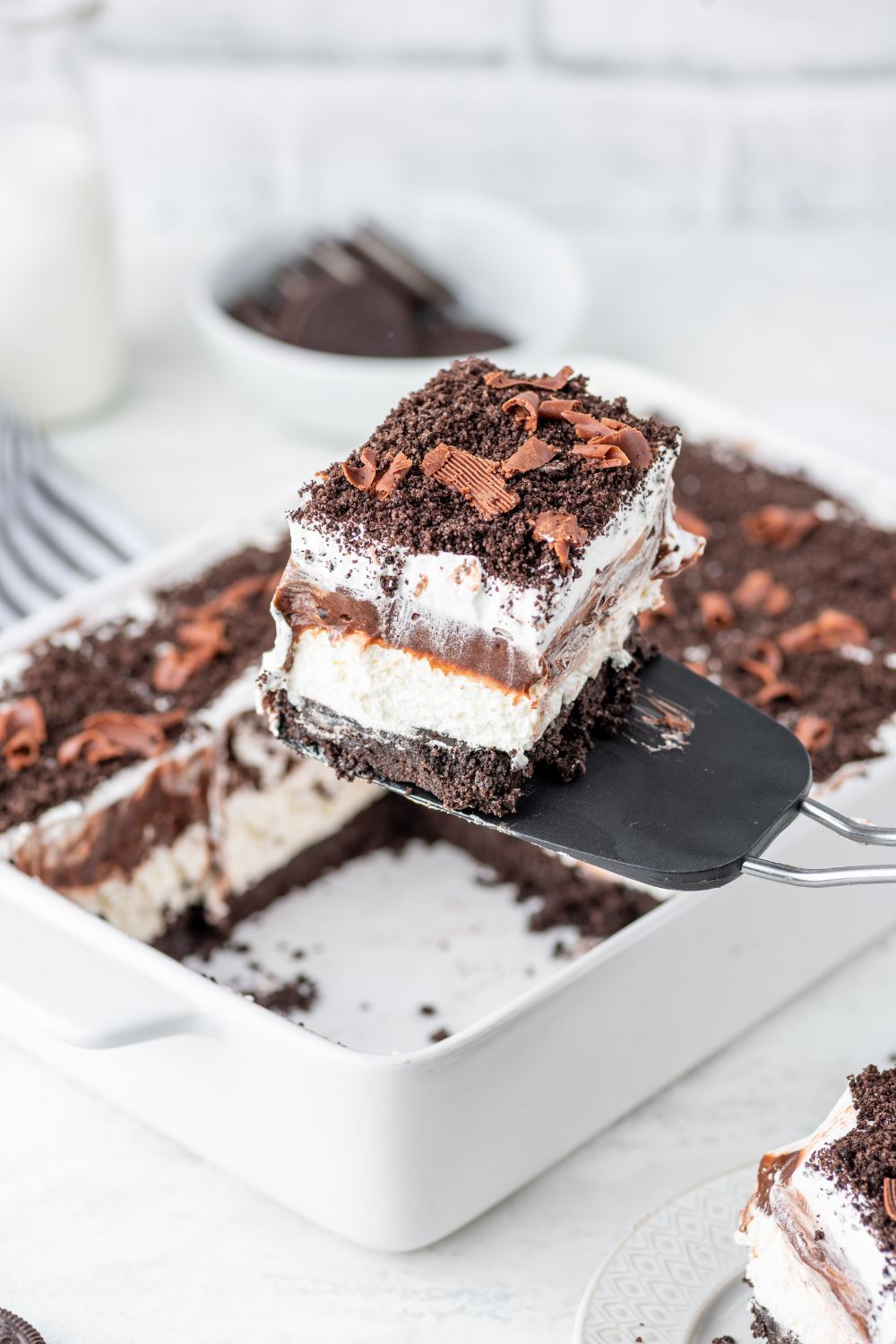 Chocolate Oreo Lush in a pan with a slice being lifted out of pan with spatula 