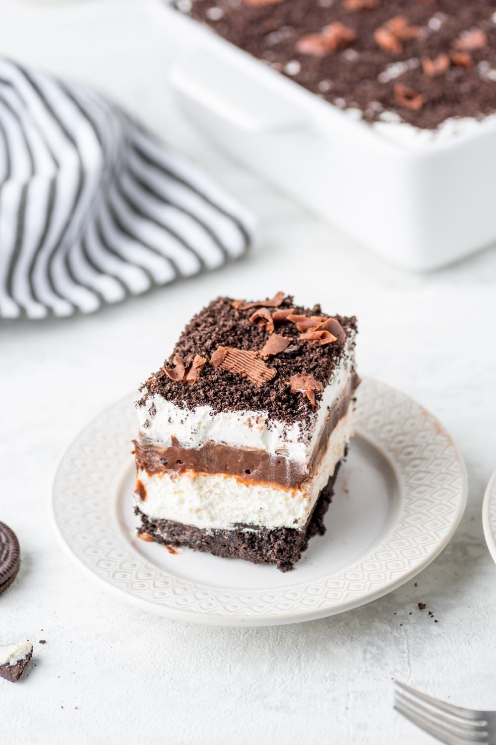 slice of Chocolate Oreo Lush on a plate with a fork in front of plate on table 