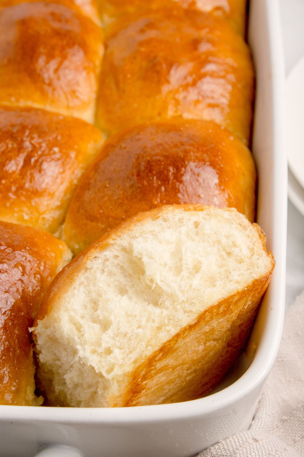 Pull Apart Rolls in a baking dish with one on the side to show the center of the dinner roll