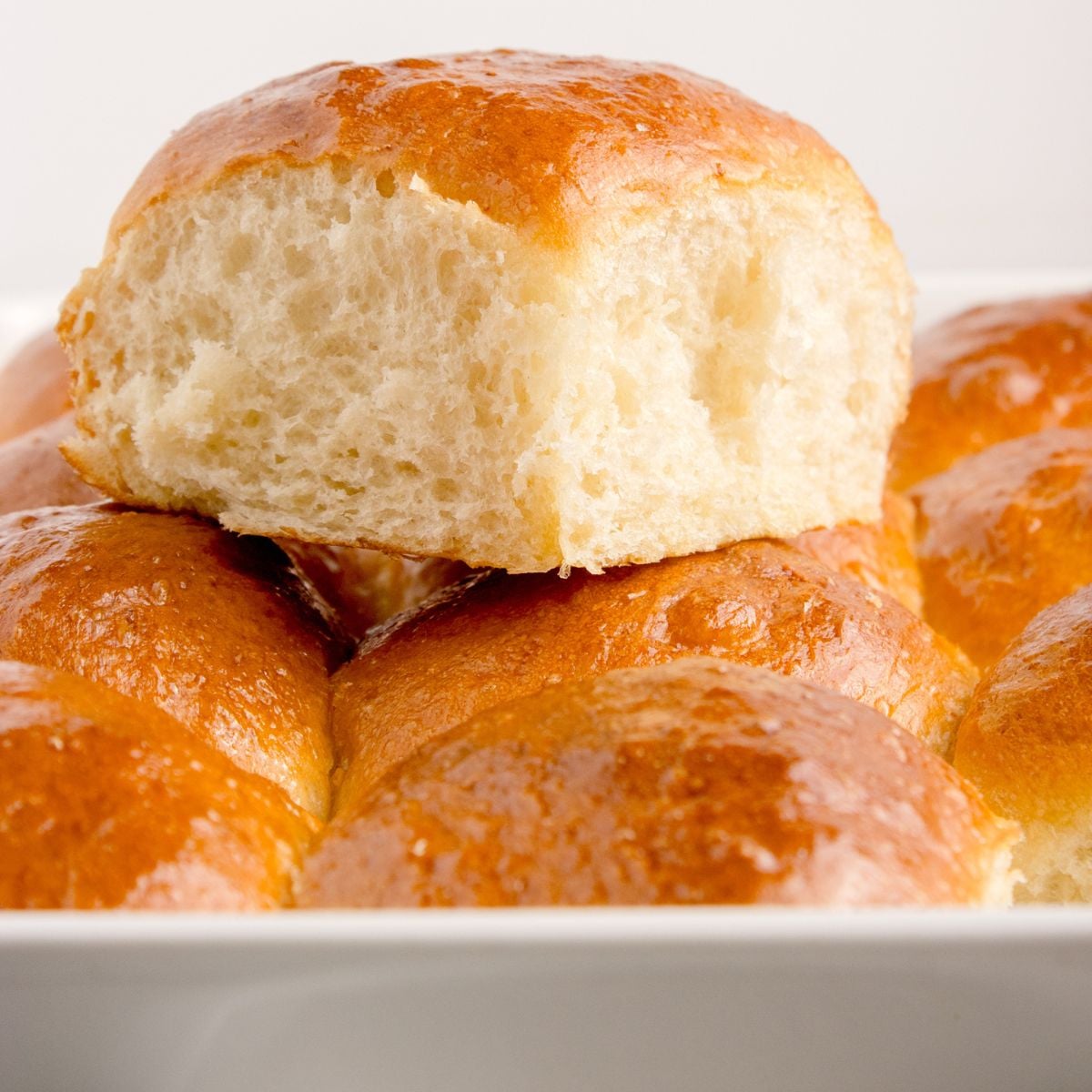 Pull Apart Dinner Rolls in a pan with one sitting on top to see how fluffy it is