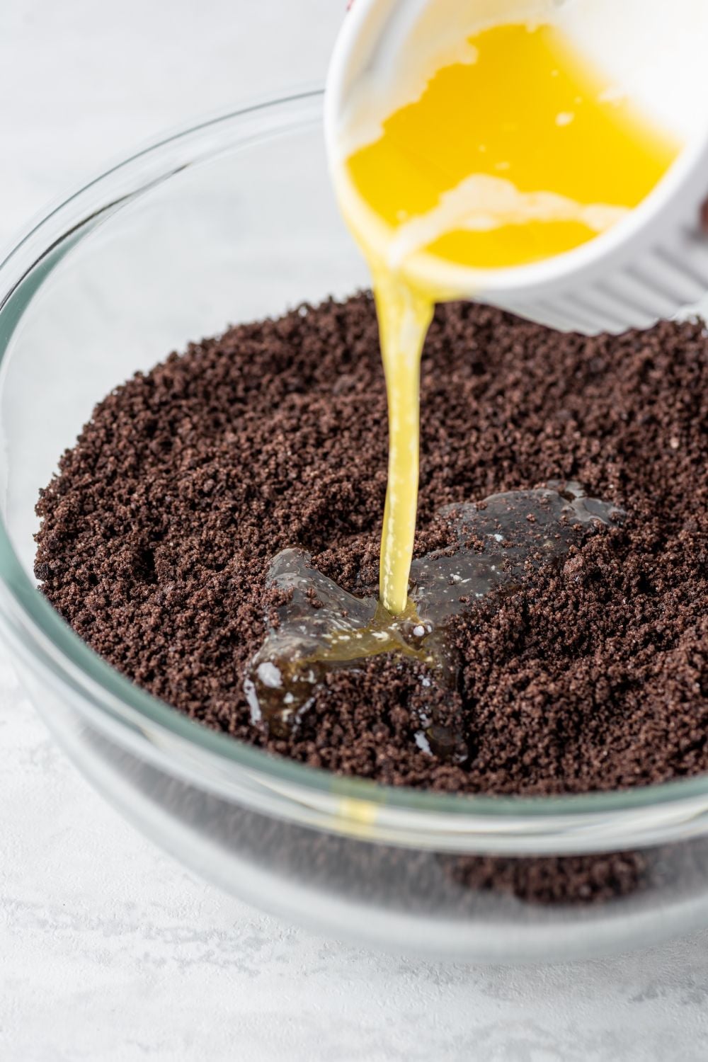 butter pouring into crushed Oreo cookies in a bowl for the Chocolate Oreo Lush