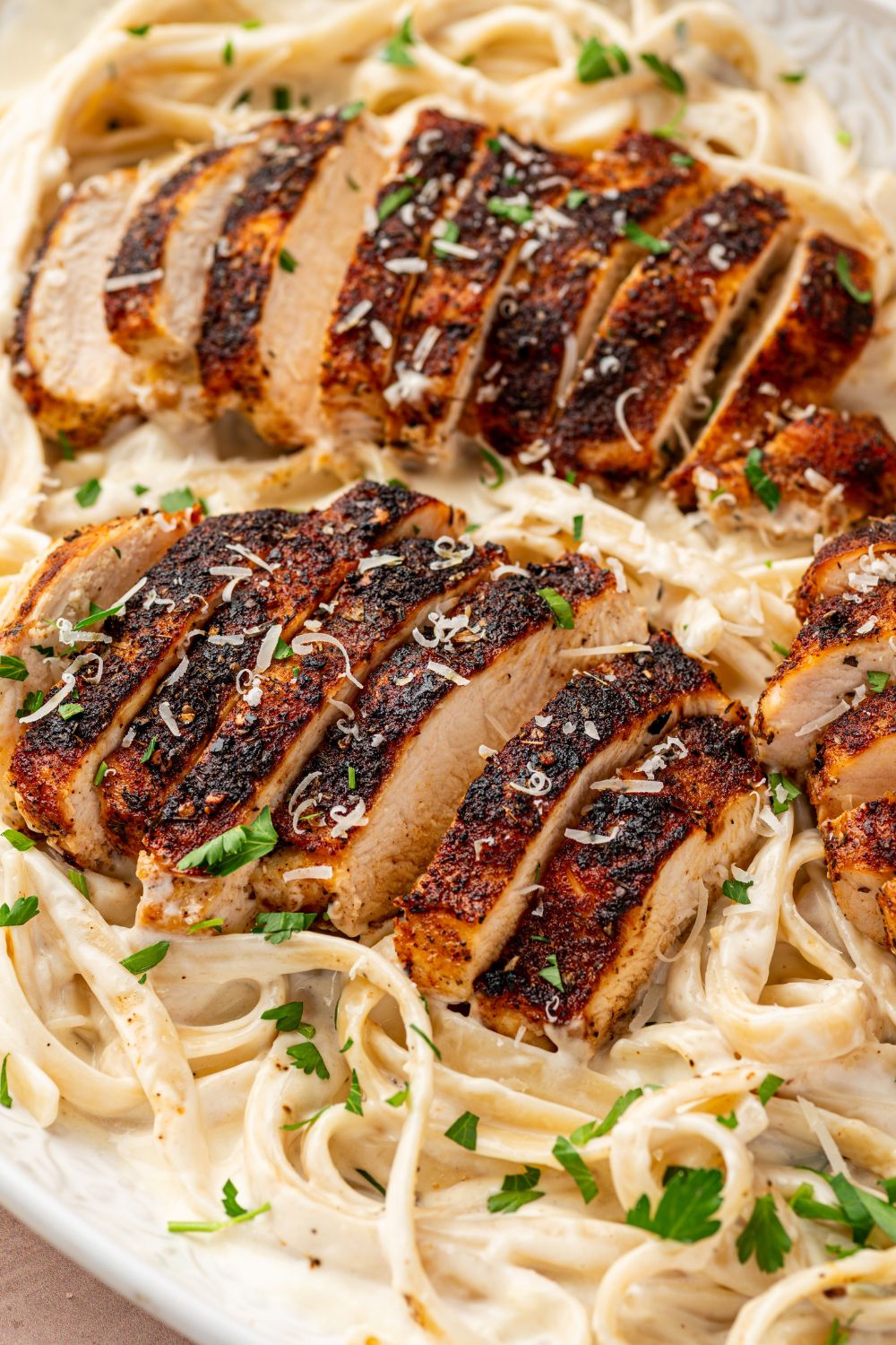 Blackened Chicken Alfredo in a platter with sliced chicken on top 