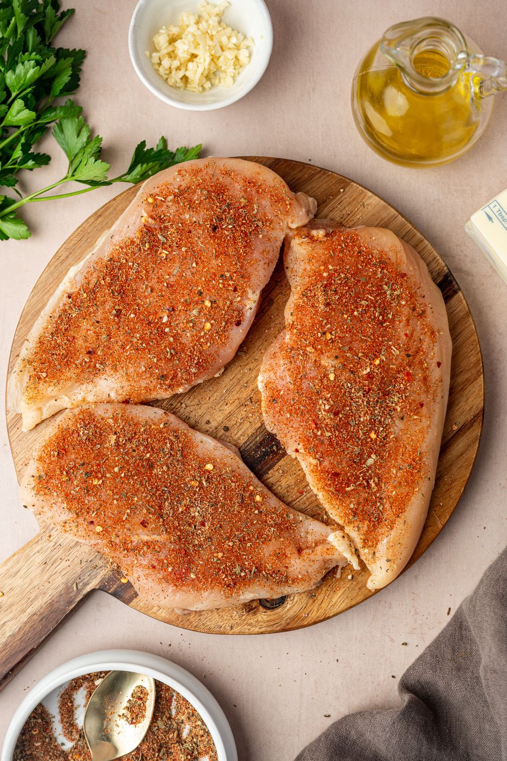raw chicken breasts that are seasoned with blackened seasoning sitting on a cutting board 