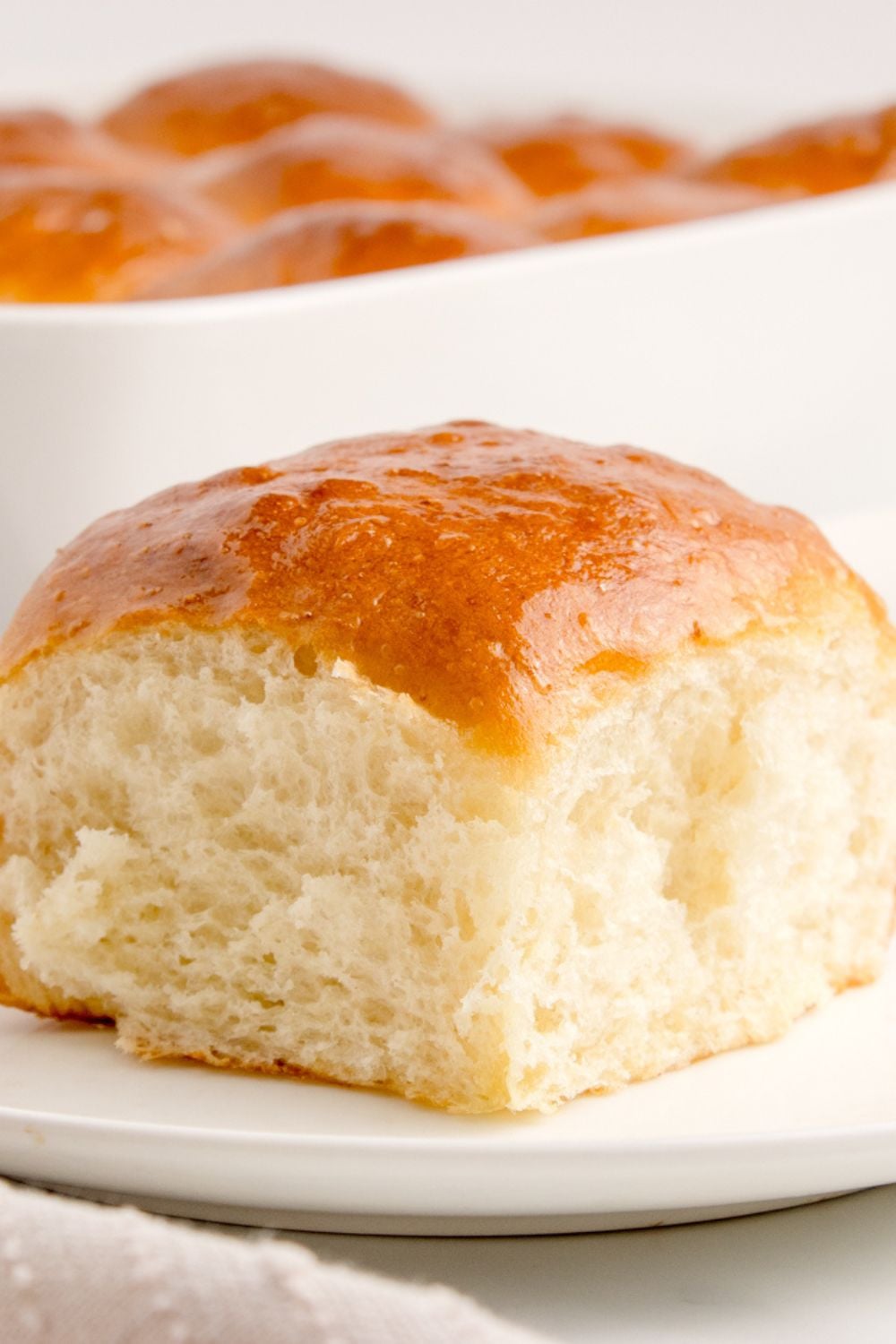 Pull Apart Roll on plate with the pan behind it with the rest of dinner rolls