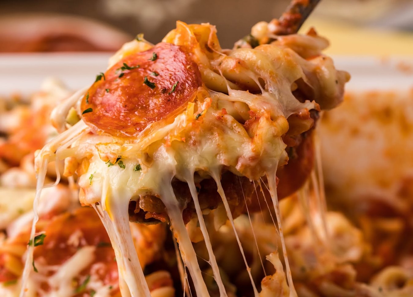 Tik Tok Pizza Pasta Casserole being lifted up by a large serving spoon