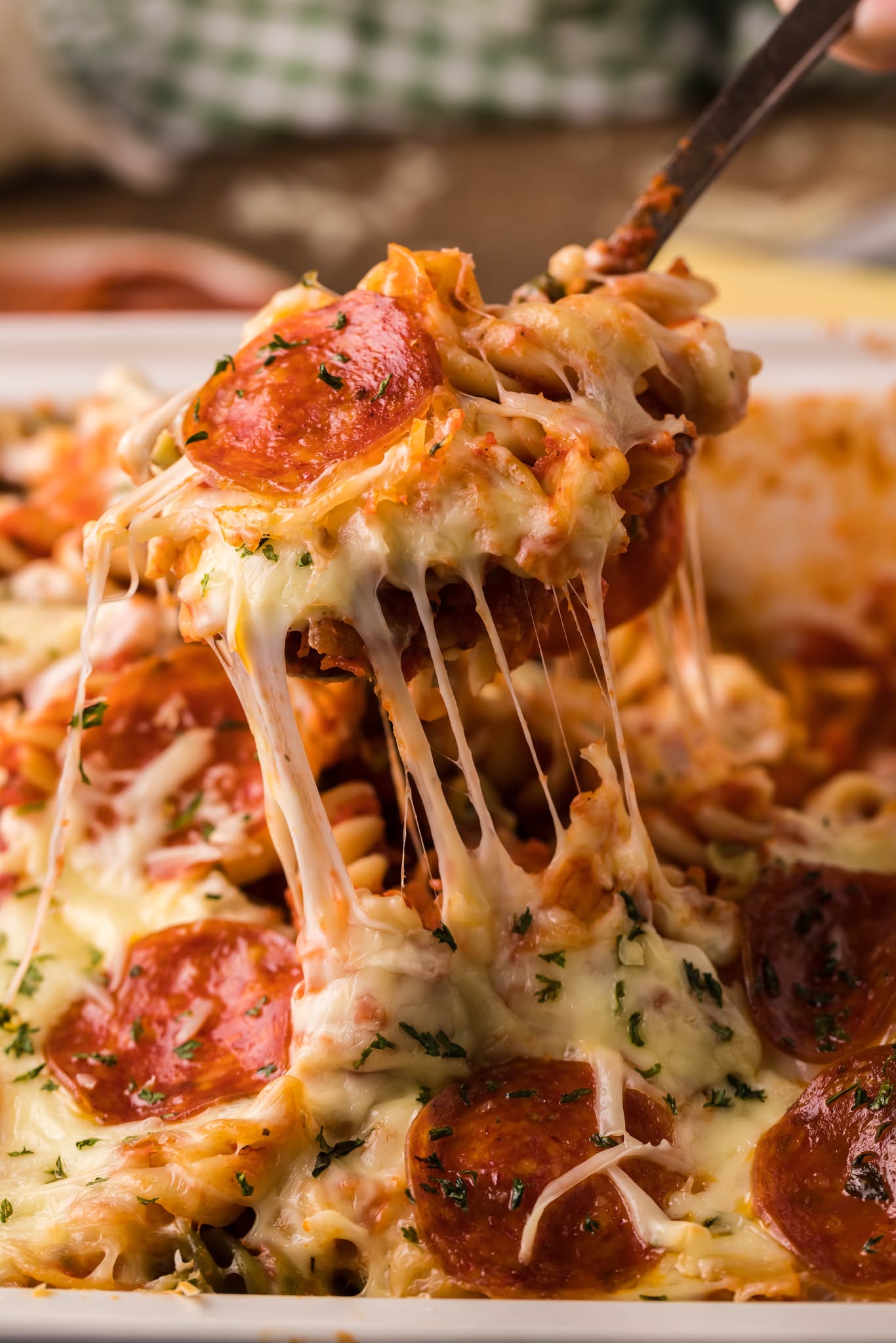 Tik Tok Pizza Pasta Casserole with a big cheesy bite being lifted out of the baking dish