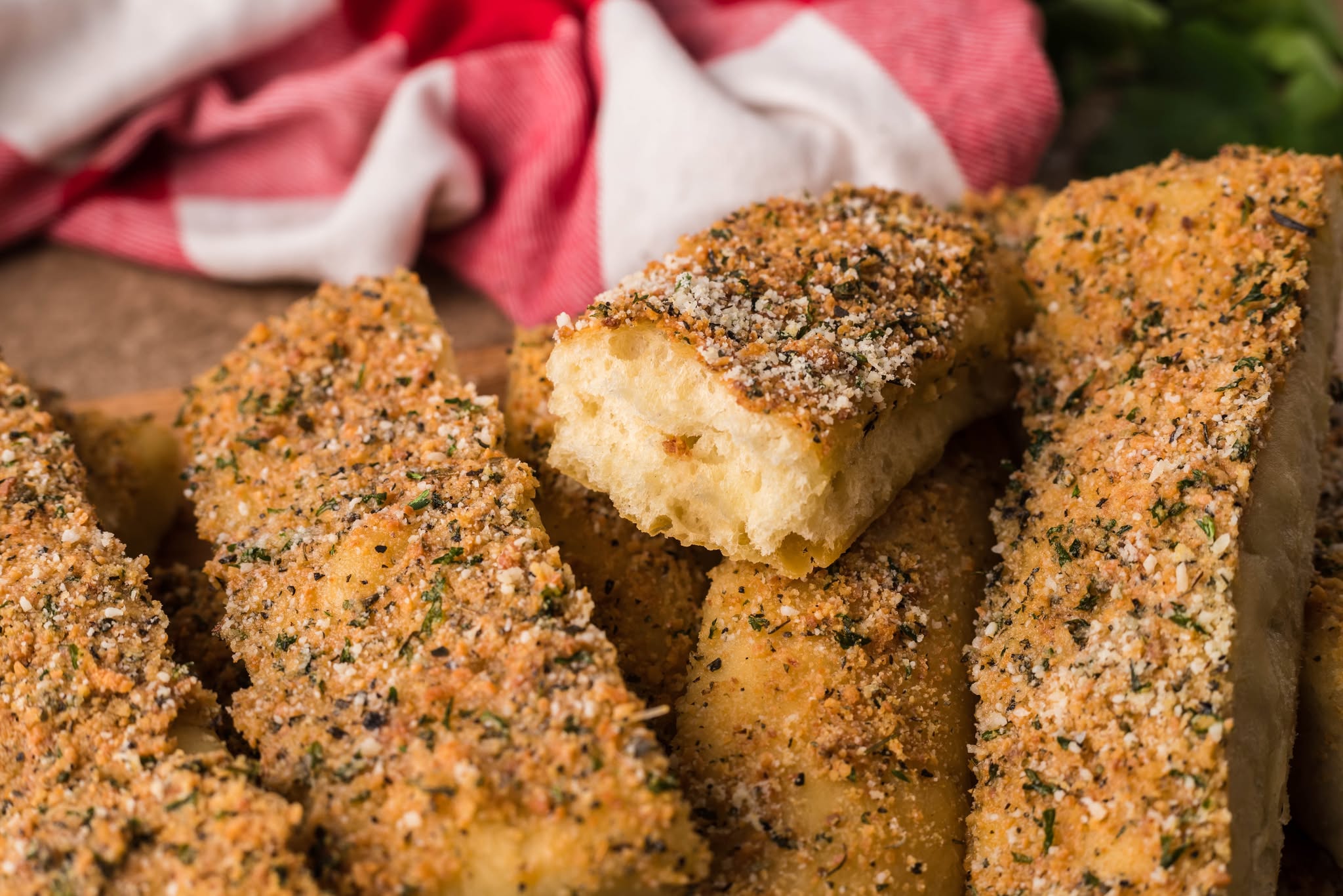 Copycat Pizza Hut Breadsticks piled in a wooden basket with one missing a bite