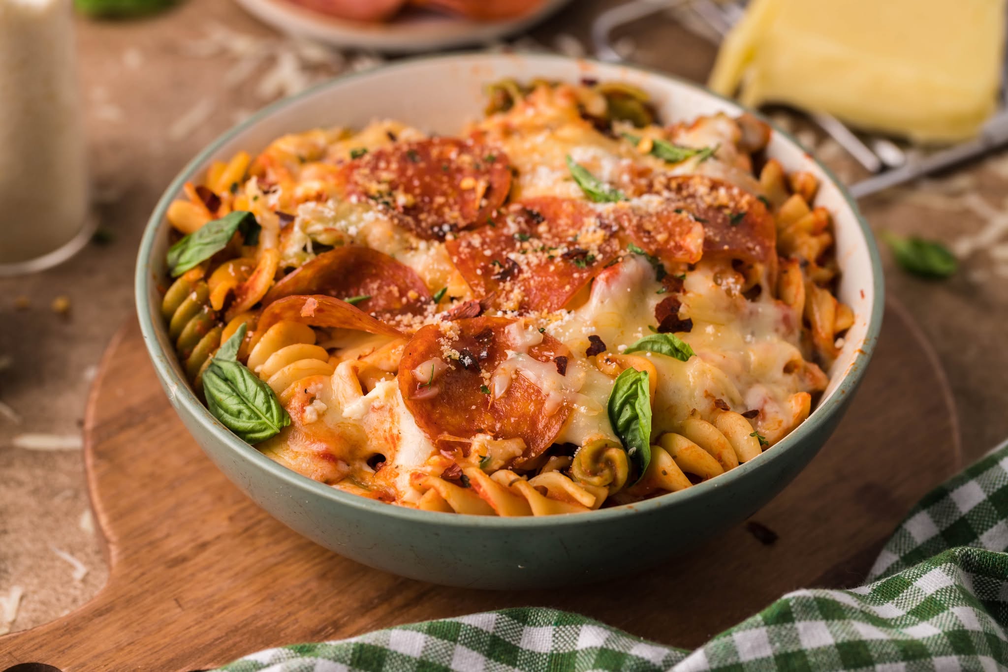 Tik Tok Pizza Pasta Casserole in a green bowl topped with parmesan cheese