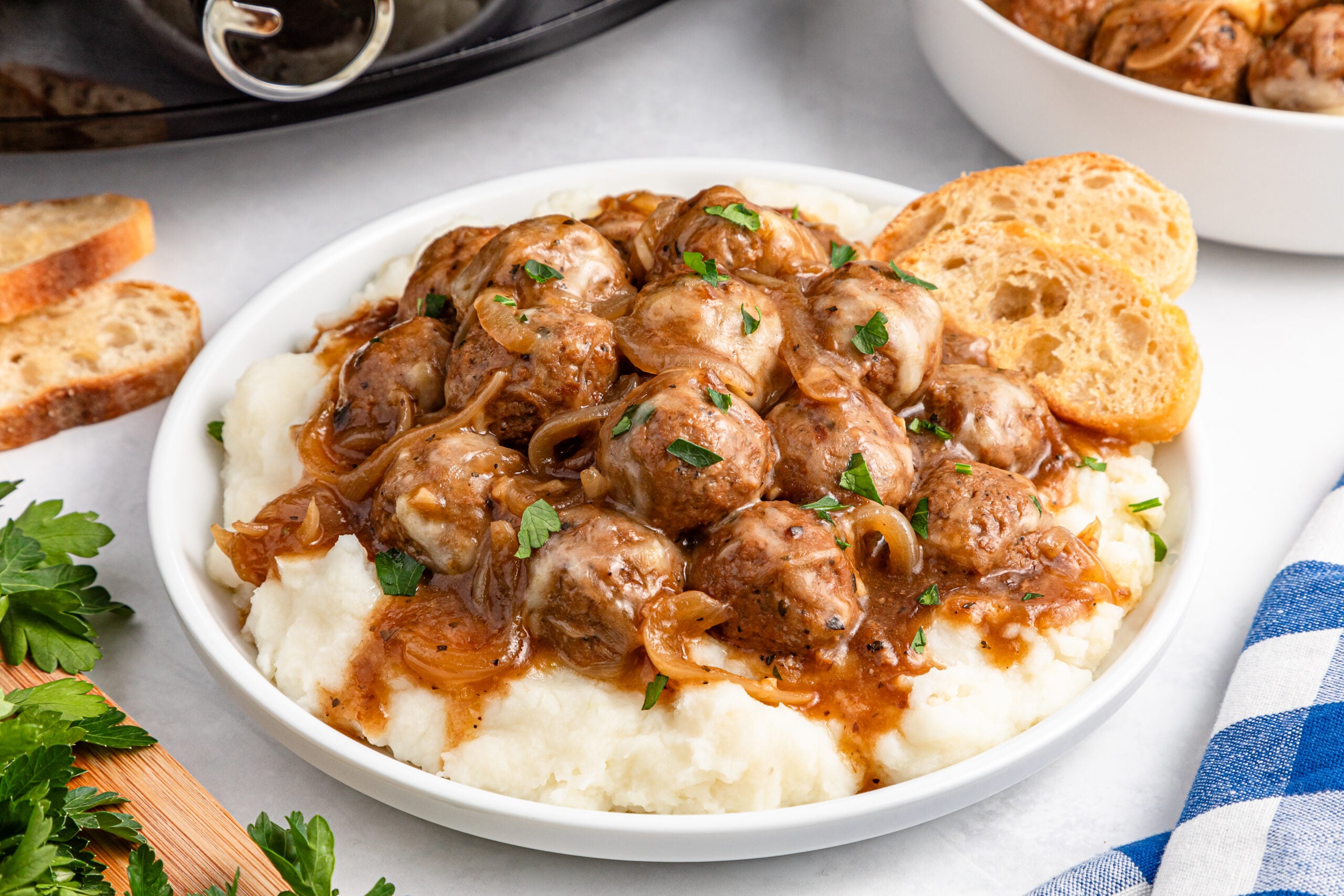 Crock Pot French Onion Meatballs on a white plate over mashed potatoes