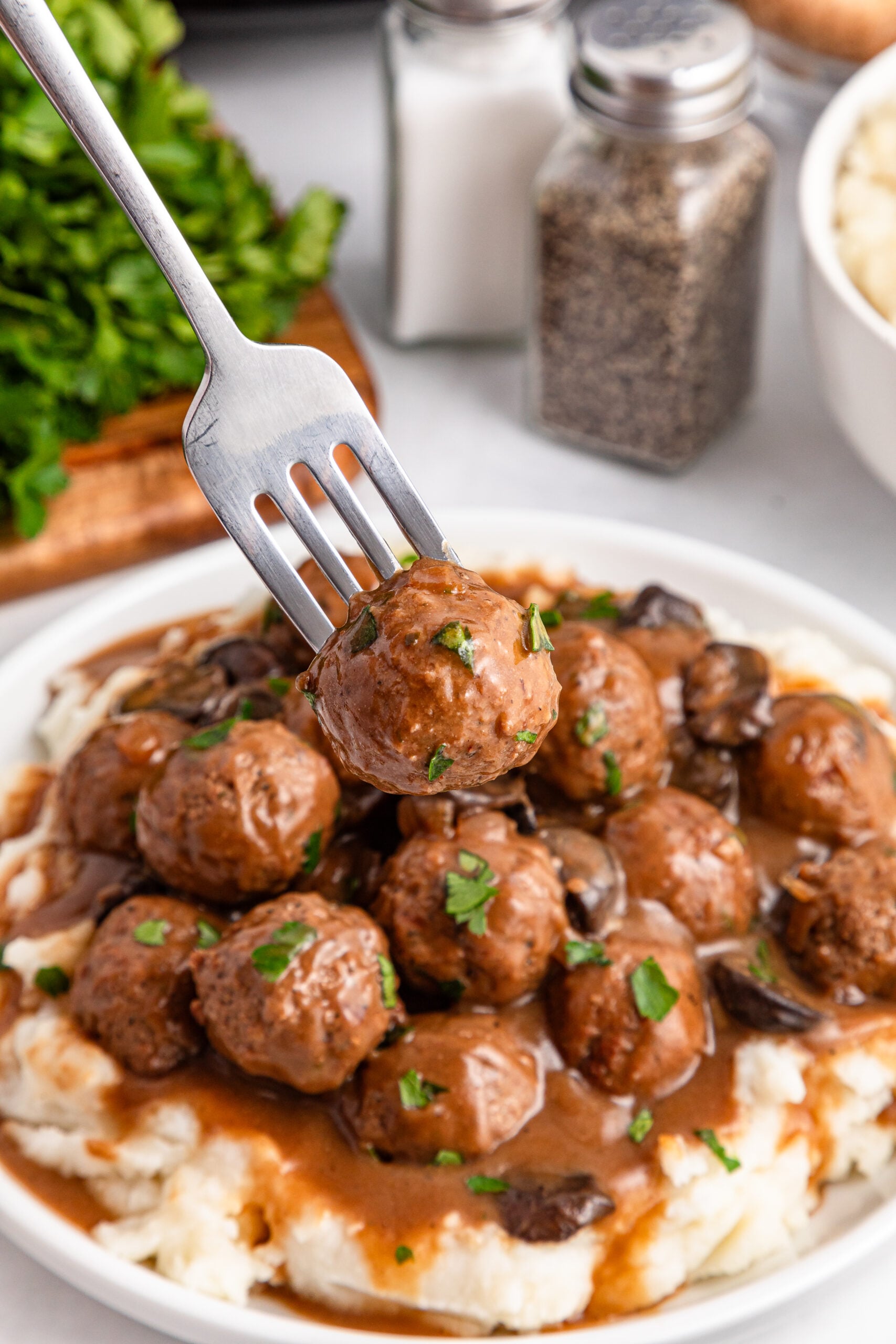 Crock Pot Salisbury Steak Meatballs over mashed potatoes in a white plate