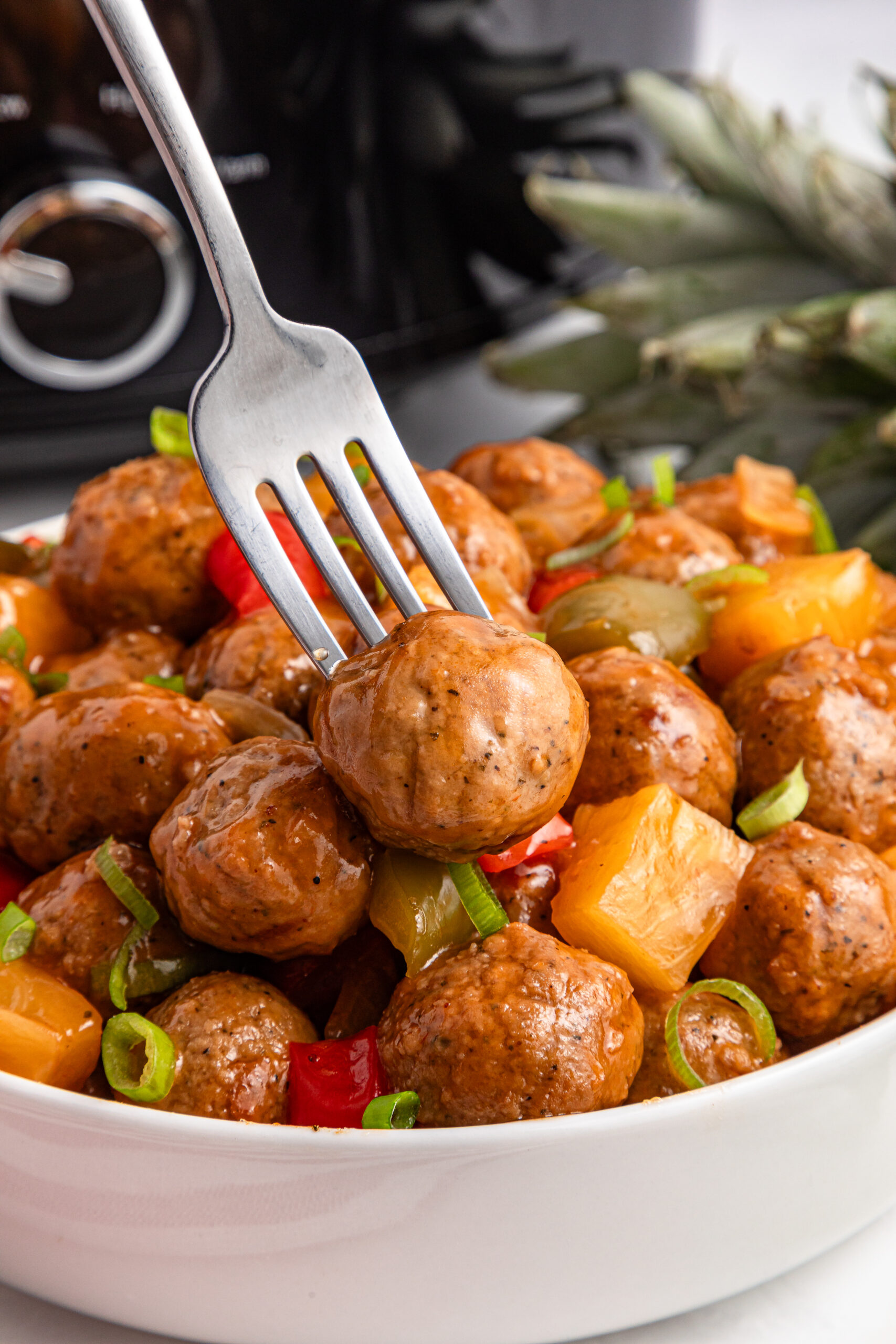 Crock Pot Sweet And Sour Meatballs in a bowl with a fork in one of the meatballs