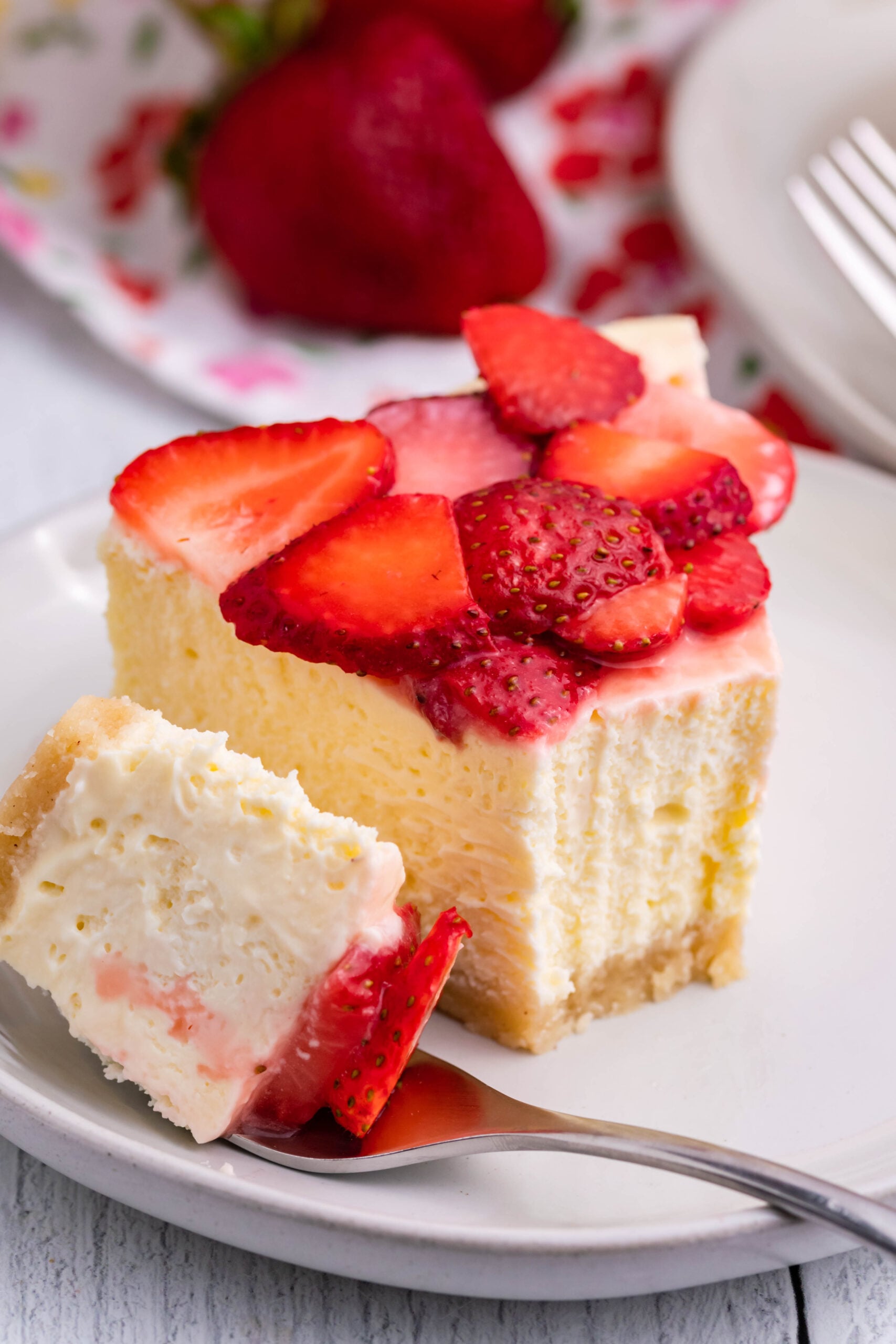 up close shot of the Keto Cheesecake on a plate topped with fresh strawberries with a bite missing