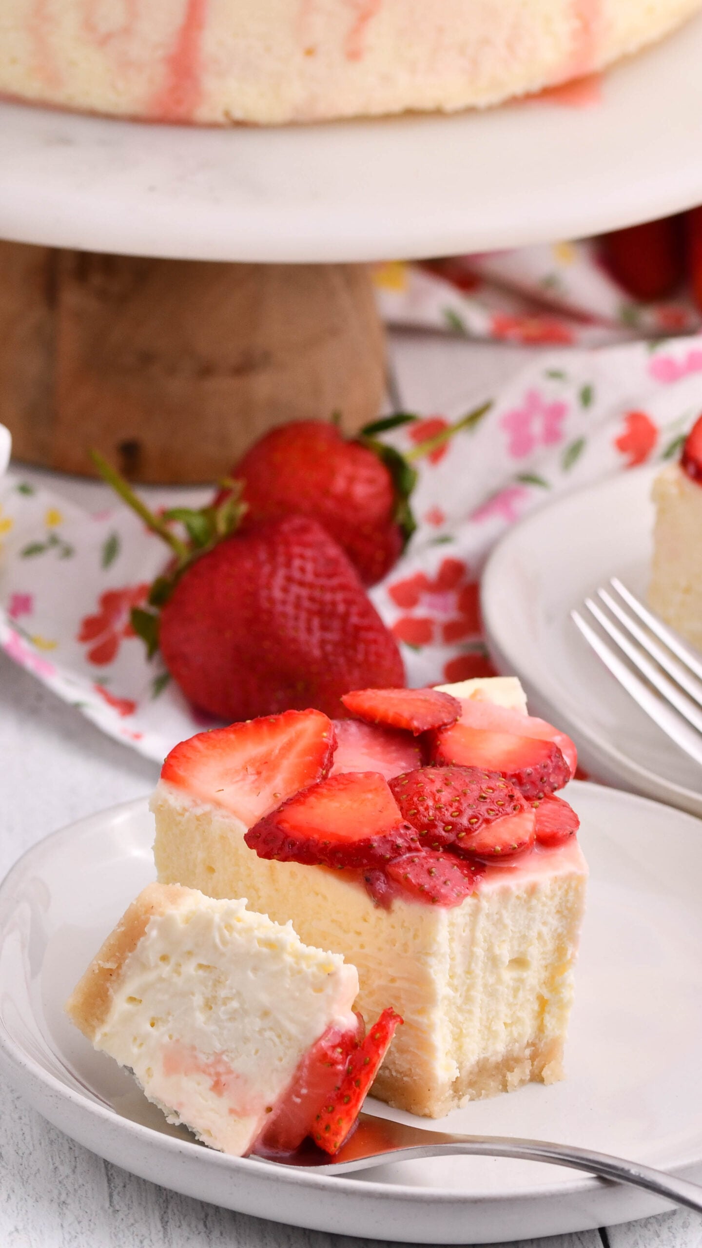 slice of keto cheesecake on a plate topped with strawberries and fork on the side of plate 