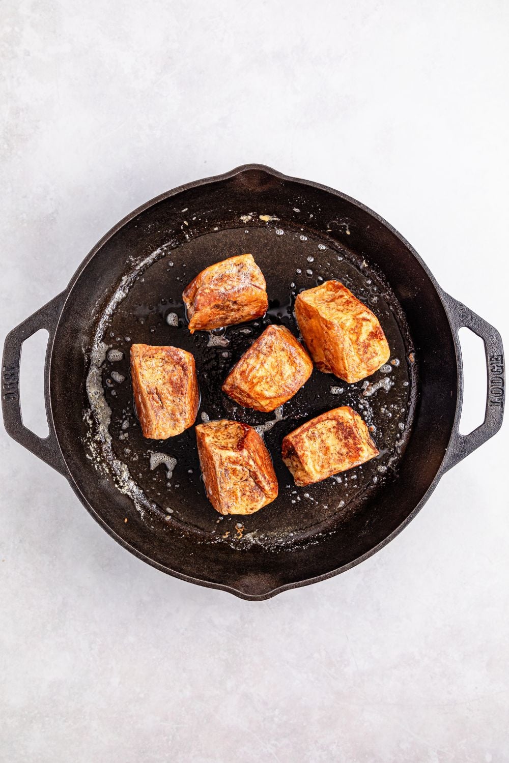 searing Hawaiian Roll French Toast in a cast iron skillet