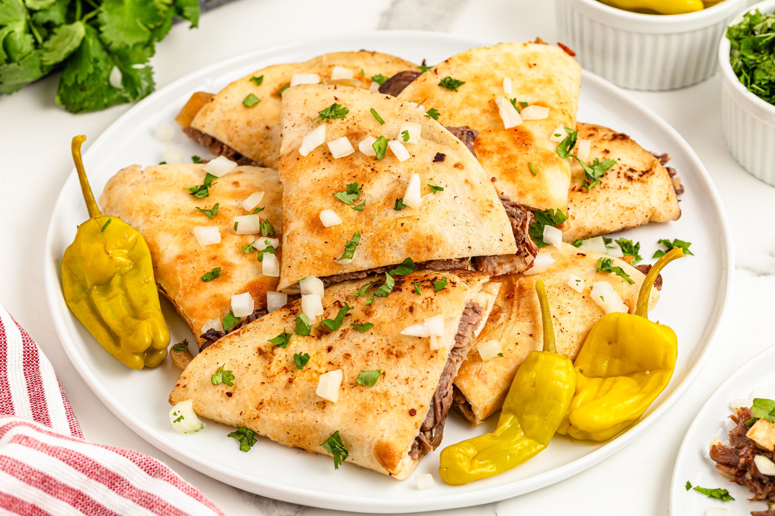 Mississippi Pot Roast Quesadillas piled on a plate topped with onions