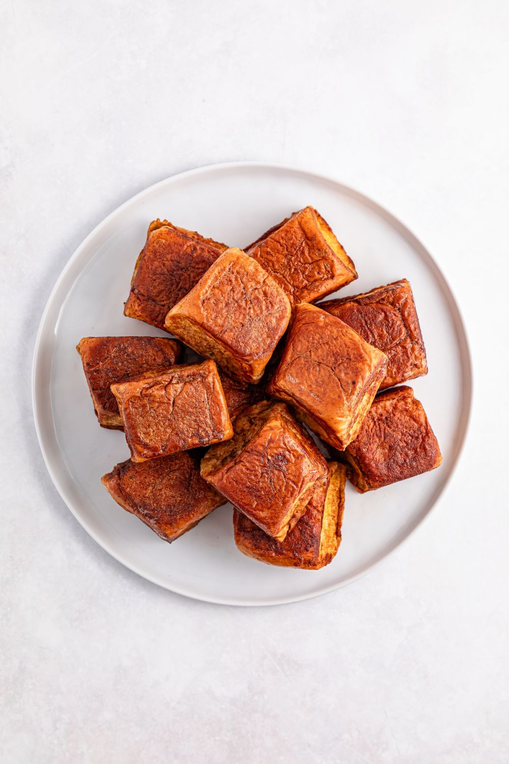 Hawaiian Roll French Toast cooked and stacked on a plate on table 